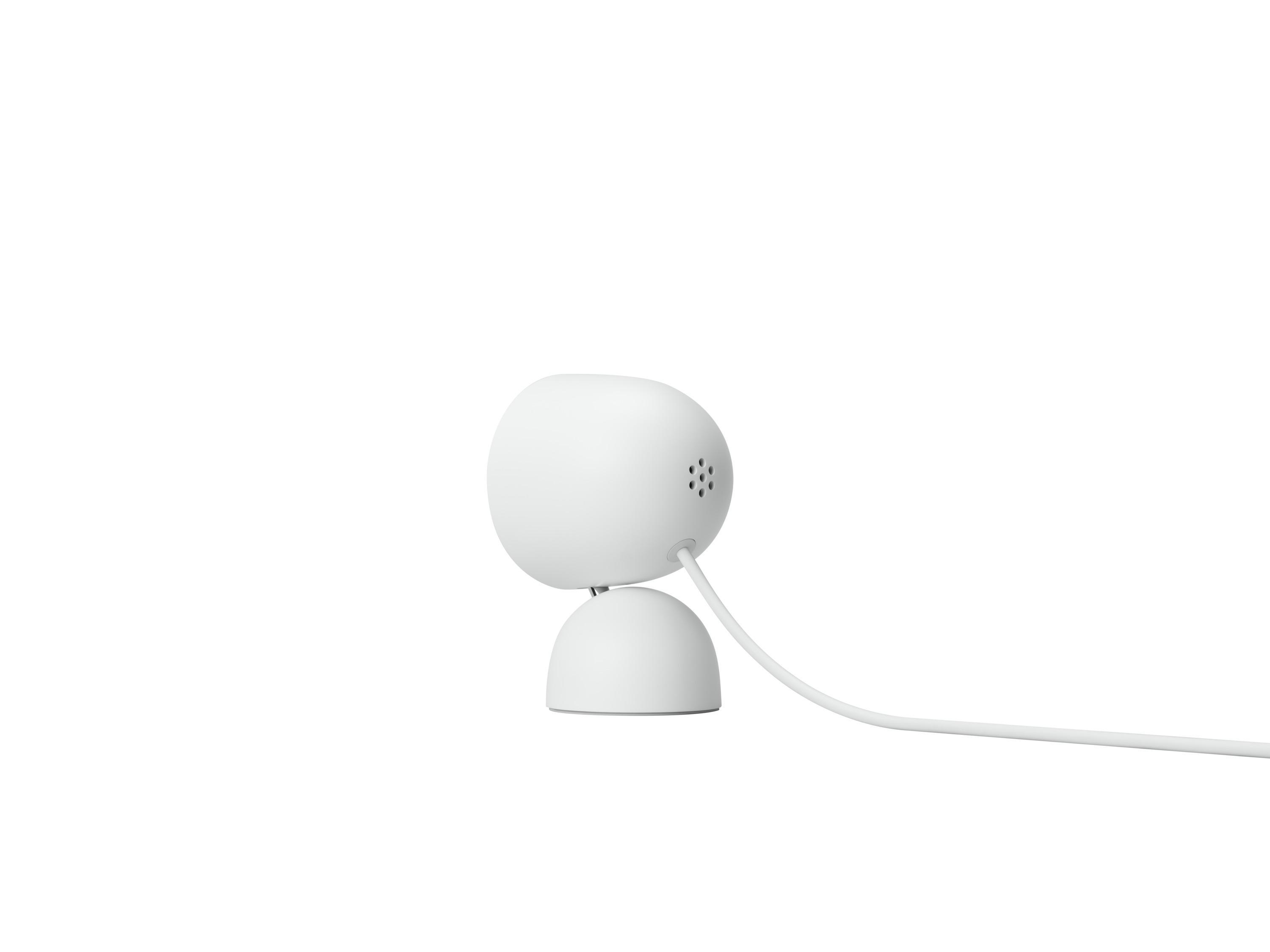 Eine weiße, abgerundete Überwachungskamera mit weißem Kabel vor weißem Hintergrund.
