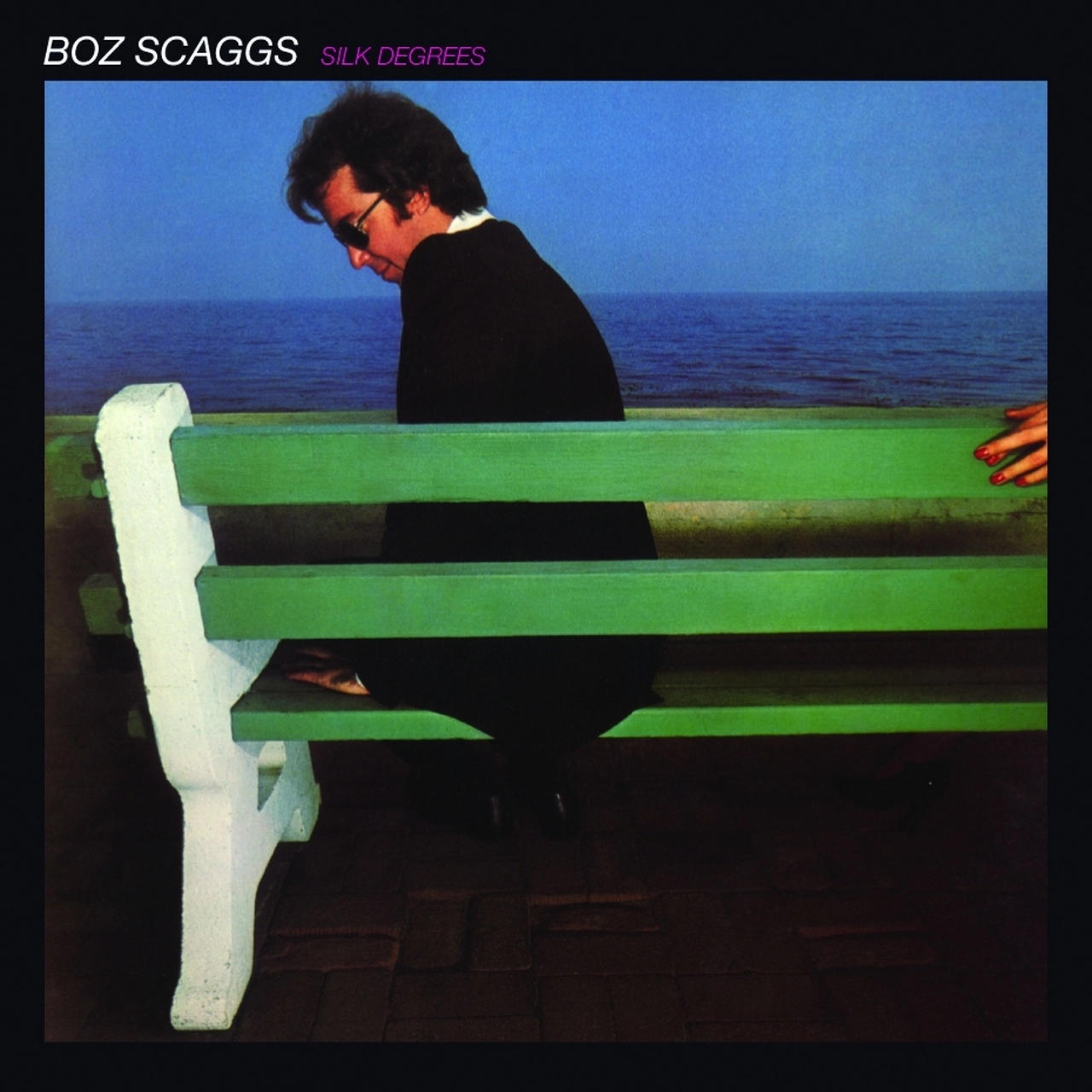 Sötét öltönyös férfi ül zöld padon a tenger mellett. BOZ SCAGGS SILK DEGREES.