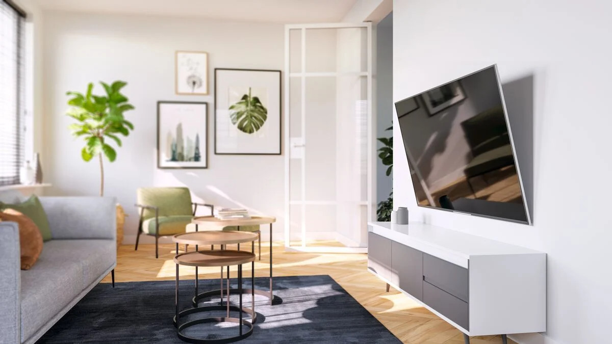 Woonkamer. Tv aan de muur, bank, salontafels en planten aanwezig.