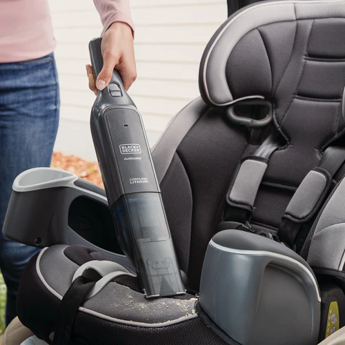 Femme utilisant un aspirateur à main noir et gris sur un siège de voiture.