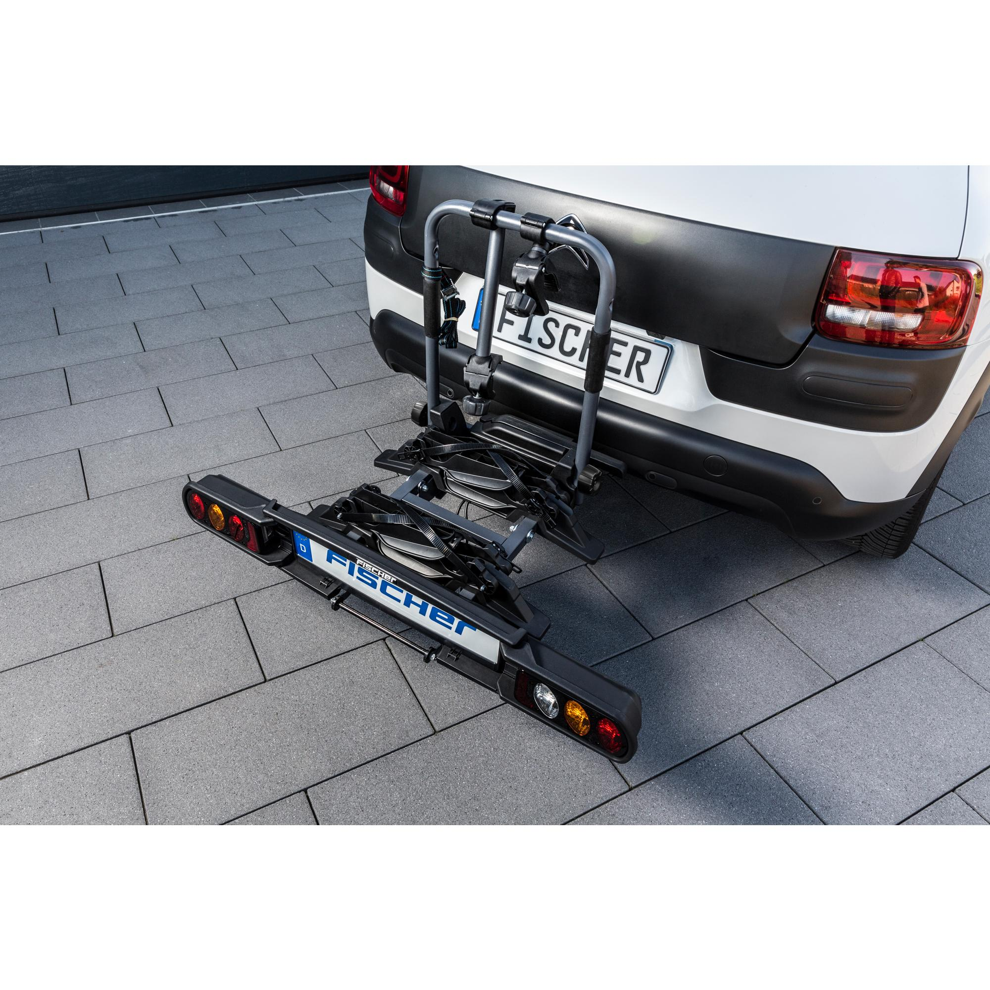 Fahrradträger am weißen Auto auf grauem Pflaster. Fischer ist geschrieben.
