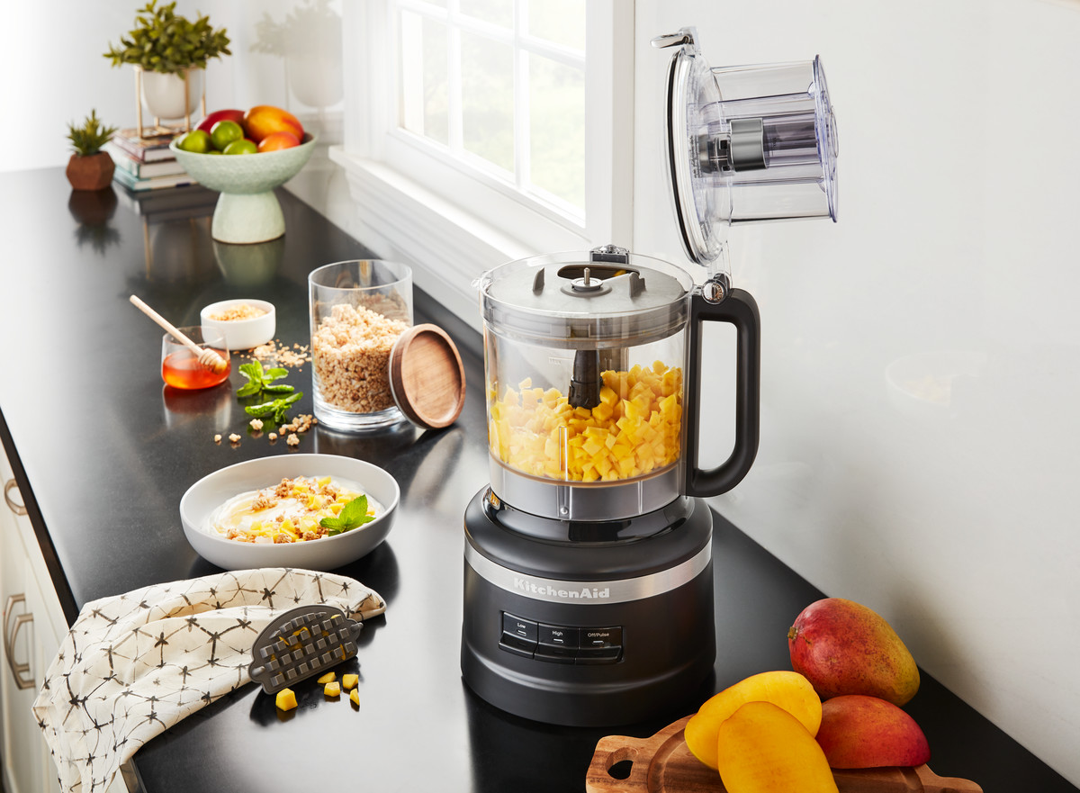 Ein schwarzer KitchenAid-Foodprozessor mit Mangos und Honig.