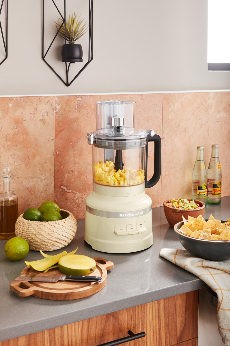 KitchenAid-Küchenmaschine mit Zutaten, Limetten, Mango auf einem Holzbrett.