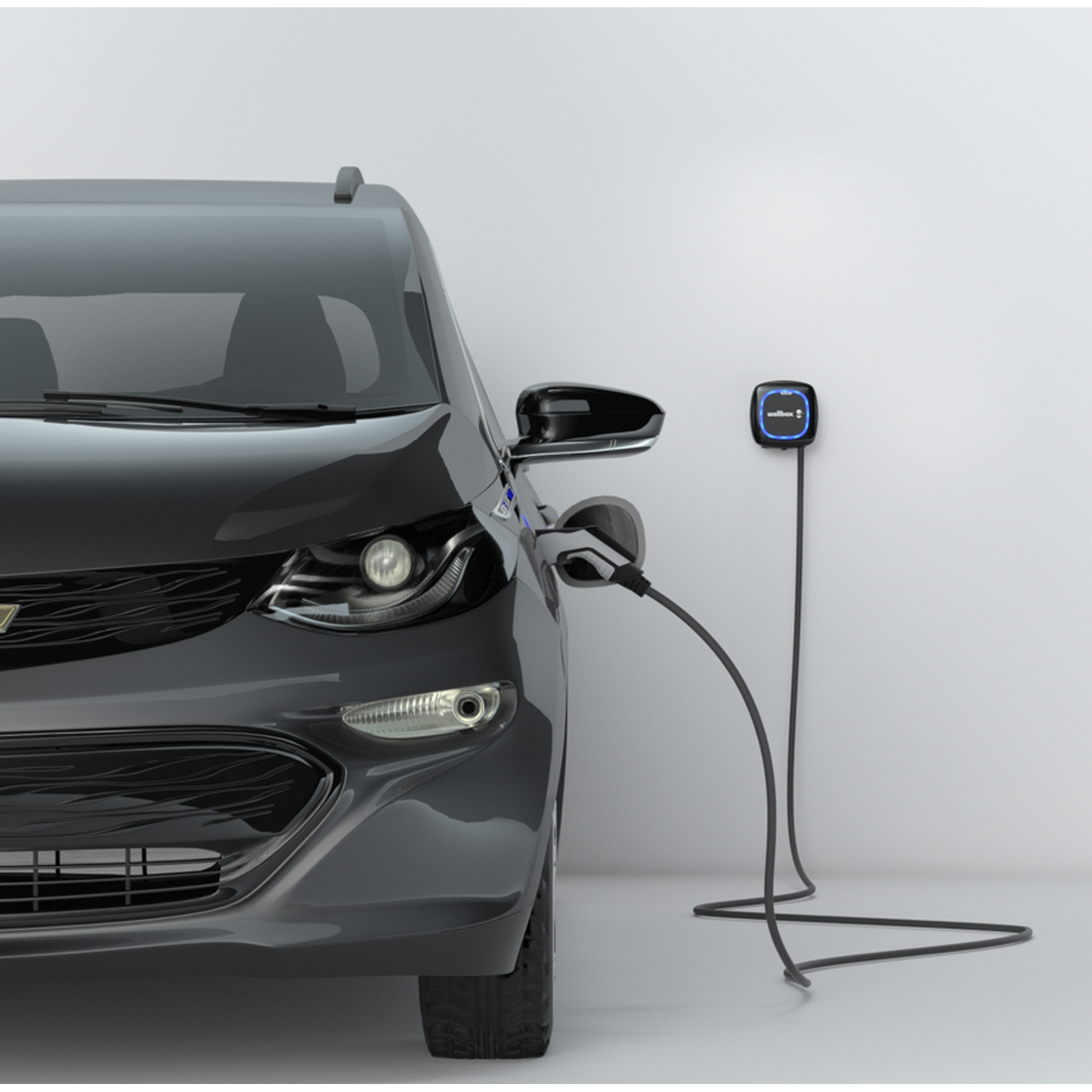Coche eléctrico negro junto a una estación de carga sobre fondo blanco.