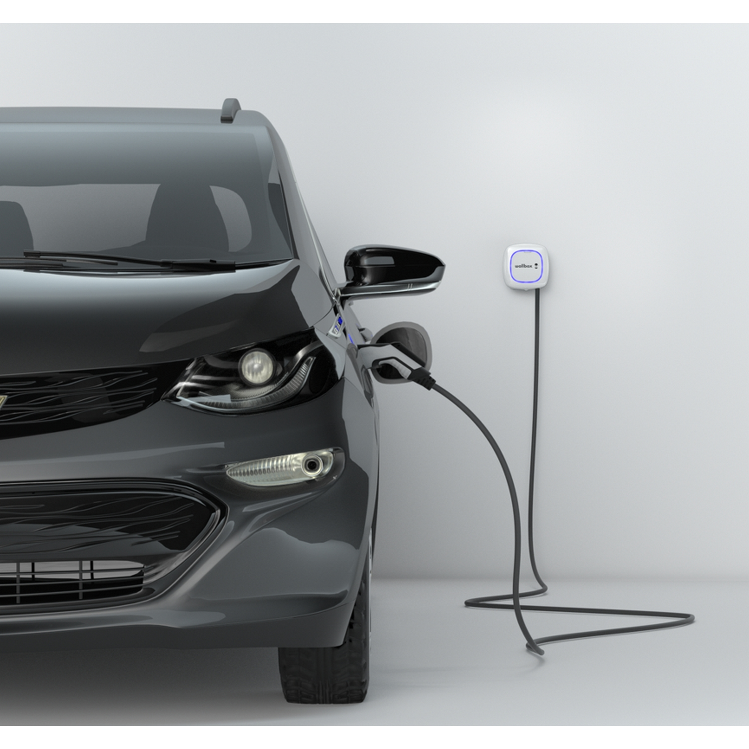 Coche eléctrico negro cargando en pared blanca con estación de carga.