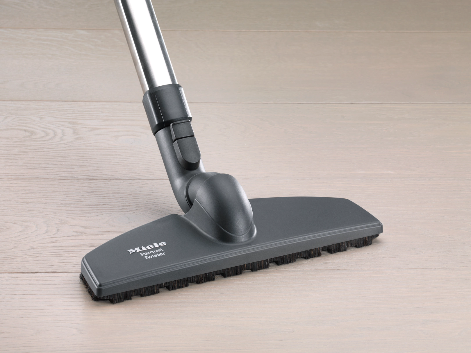 Tête d'aspirateur sur parquet. La marque Miele Parquet Twister est visible.