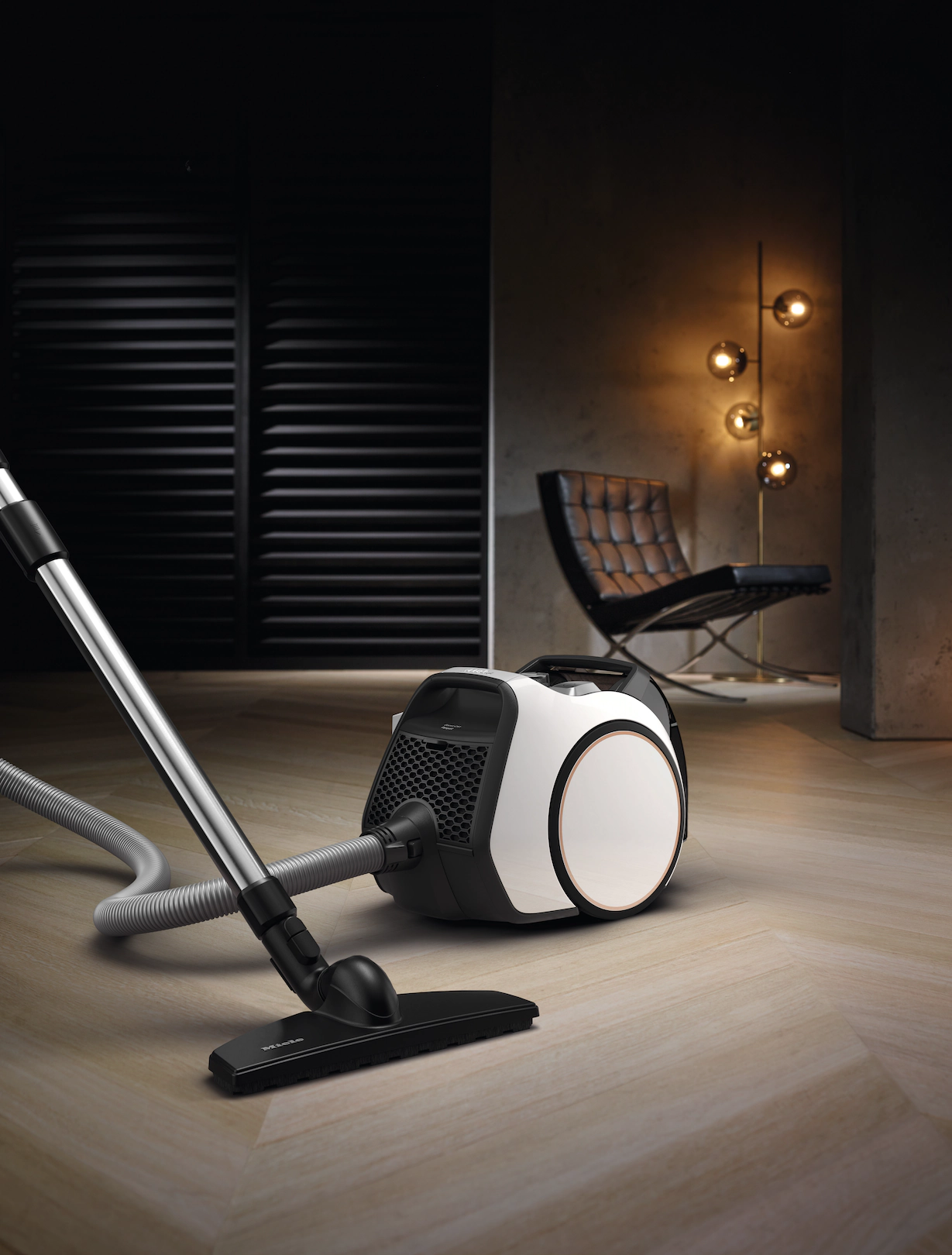 Un aspirateur avec un corps noir et blanc sur un sol en bois, dans une pièce moderne.