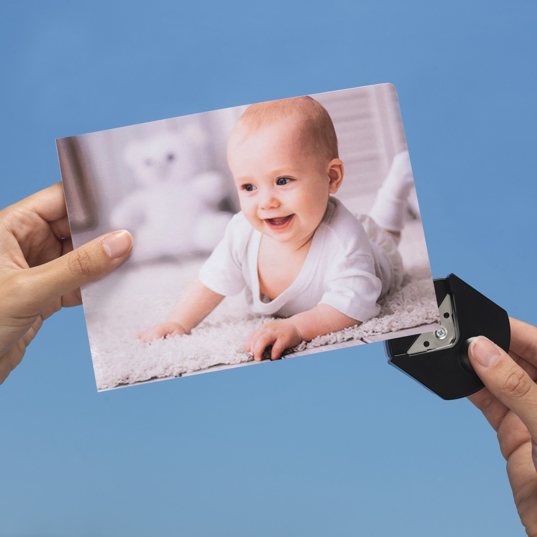 Ein Baby lächelt auf einem Foto, das in Händen gehalten wird, mit einem Eckenabschneider.