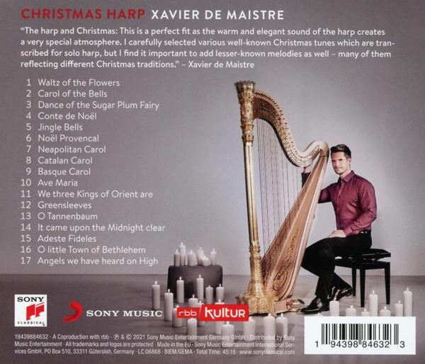 Ein Mann in rotem Hemd spielt eine goldene Harfe. Kerzen im Hintergrund.