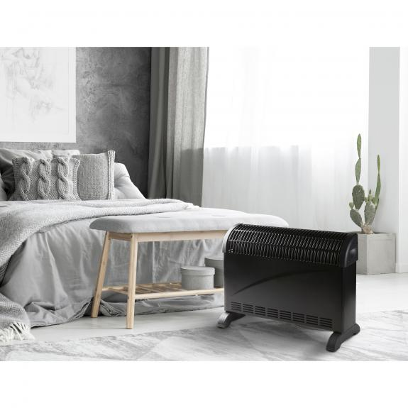 Bedroom scene with bed, bench, heater. Gray and white decor. Cactus in corner.