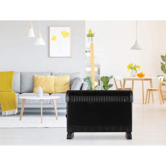 Black electric heater in a living room with white walls, grey sofa, and yellow accents.