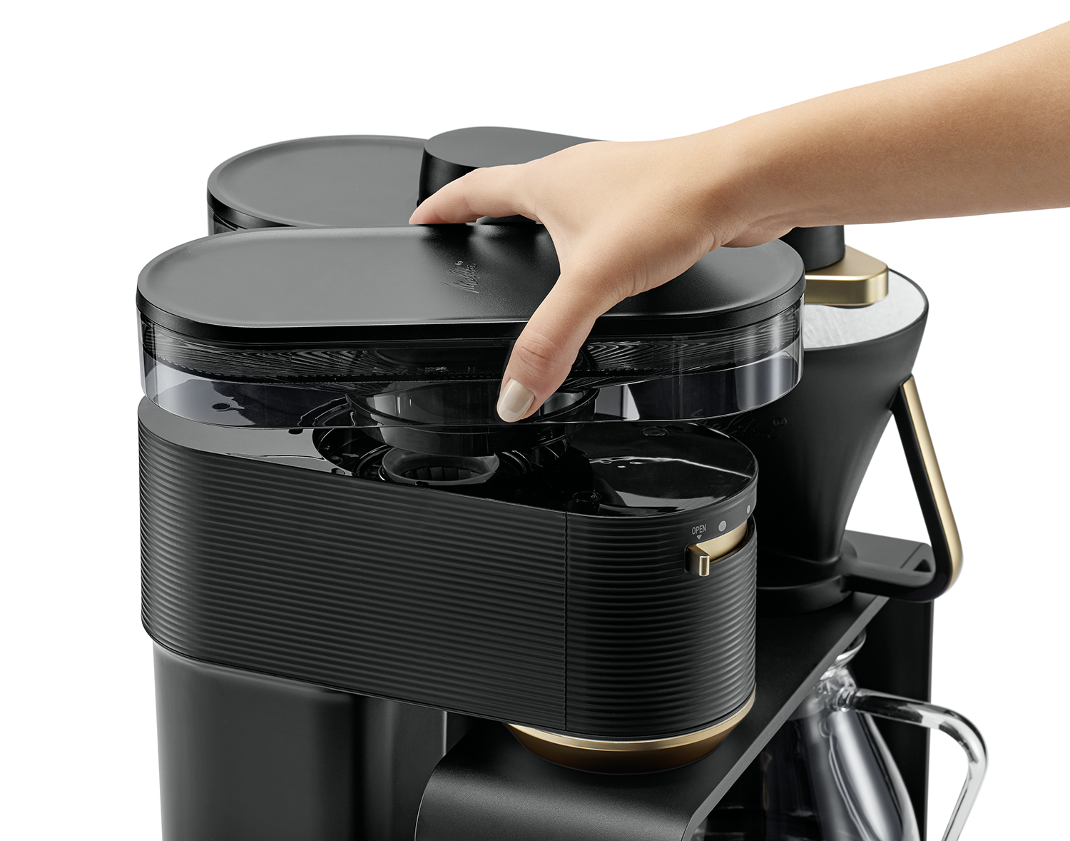 Een hand die het deksel van een zwarte koffiemachine opent.