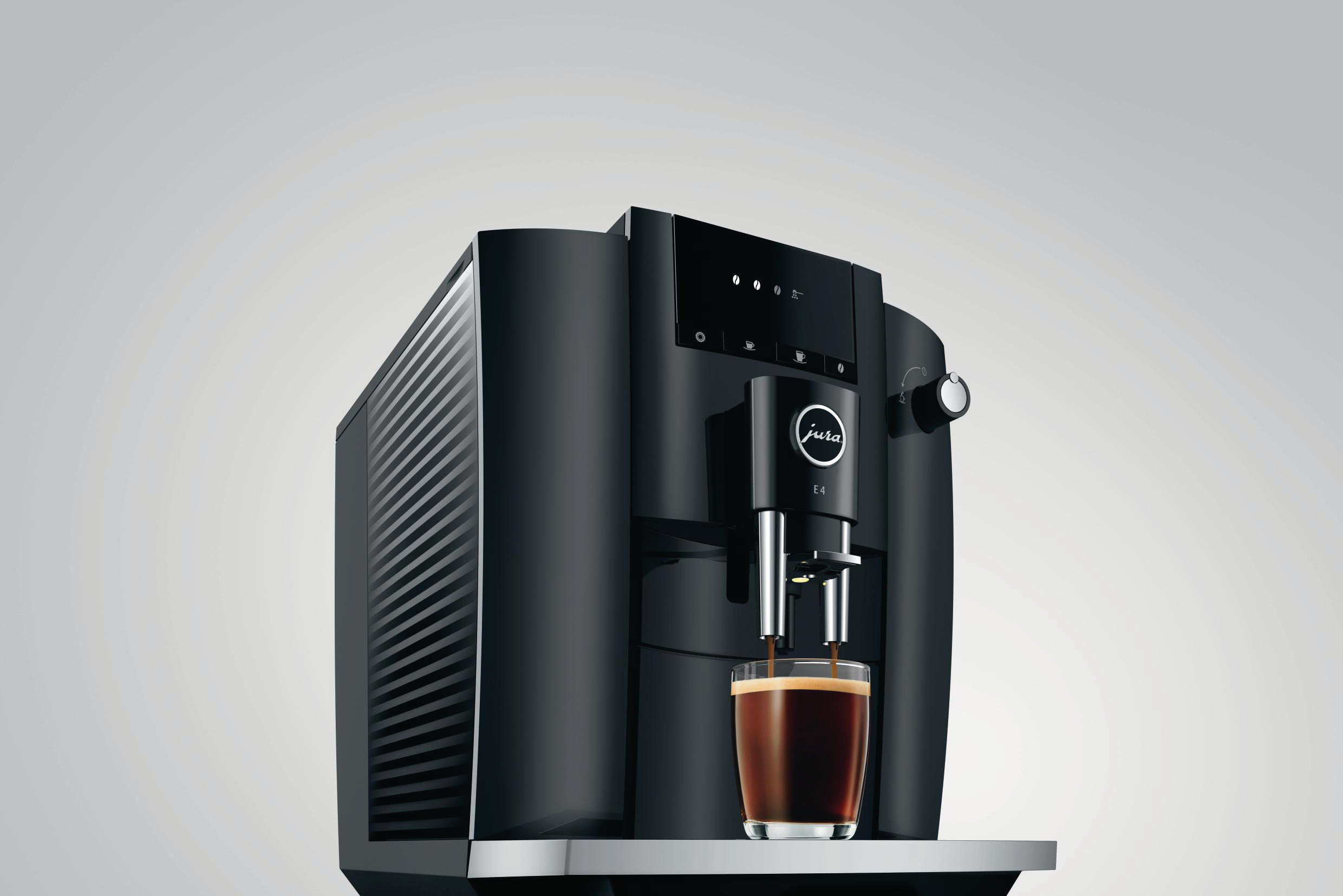 Eine schwarze Jura E4 Kaffeemaschine mit einem Glas Kaffee.