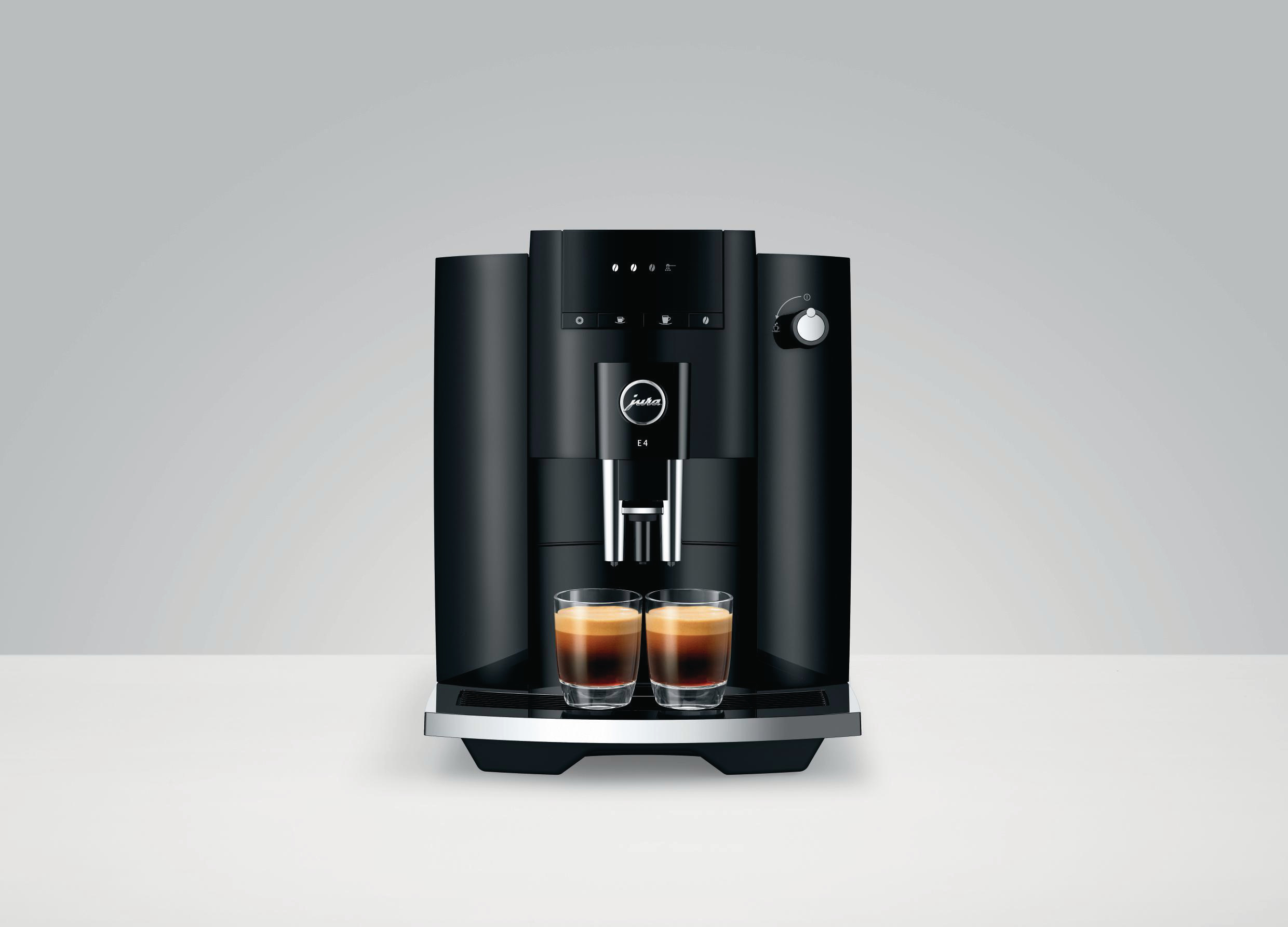 Eine schwarze Kaffeemaschine mit zwei Espresso-Gläsern auf einem weißen Tisch.