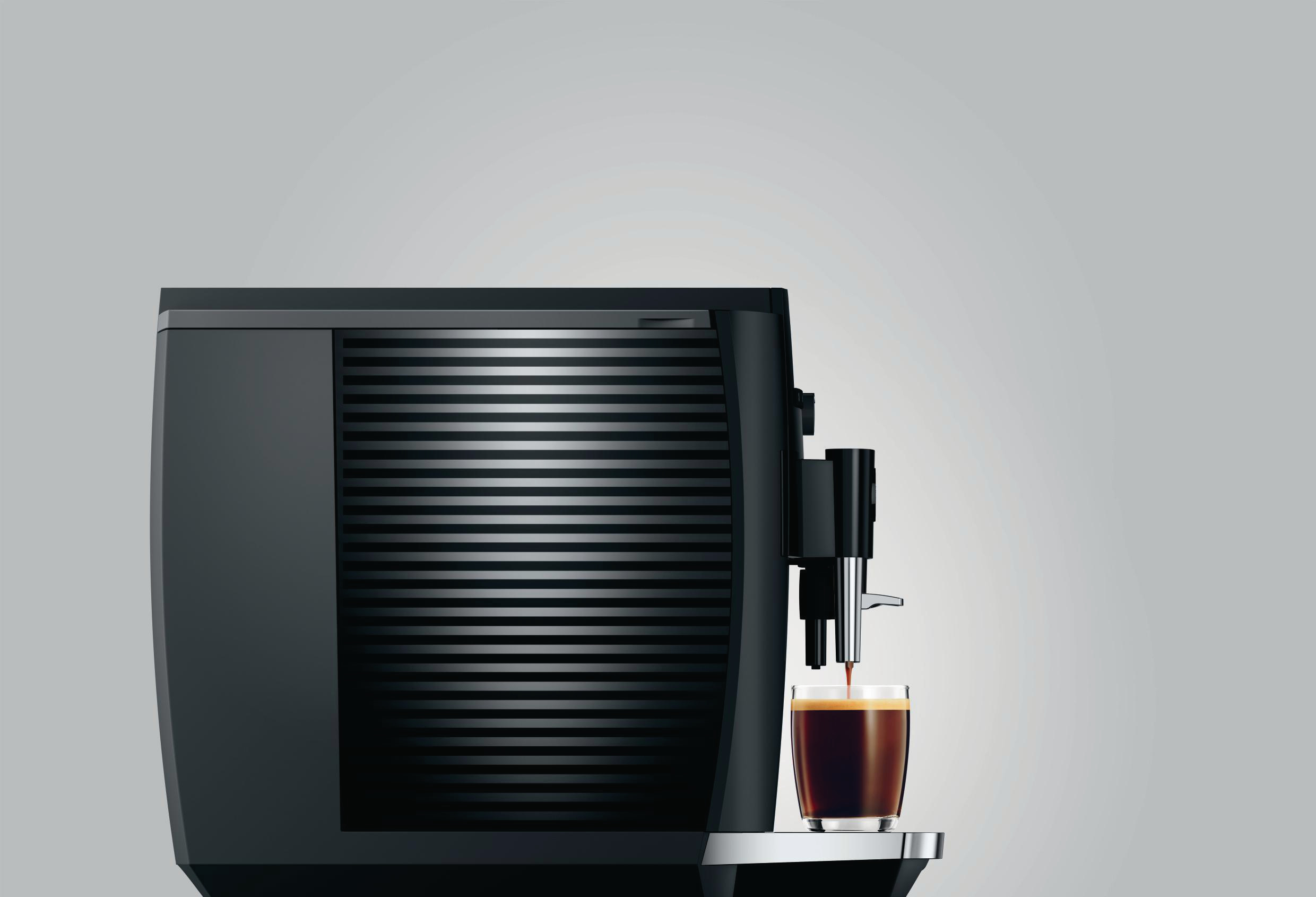 Eine schwarze Kaffeemaschine, die Kaffee in ein Glas ausgibt. Die Maschine hat eine gerippte Front.