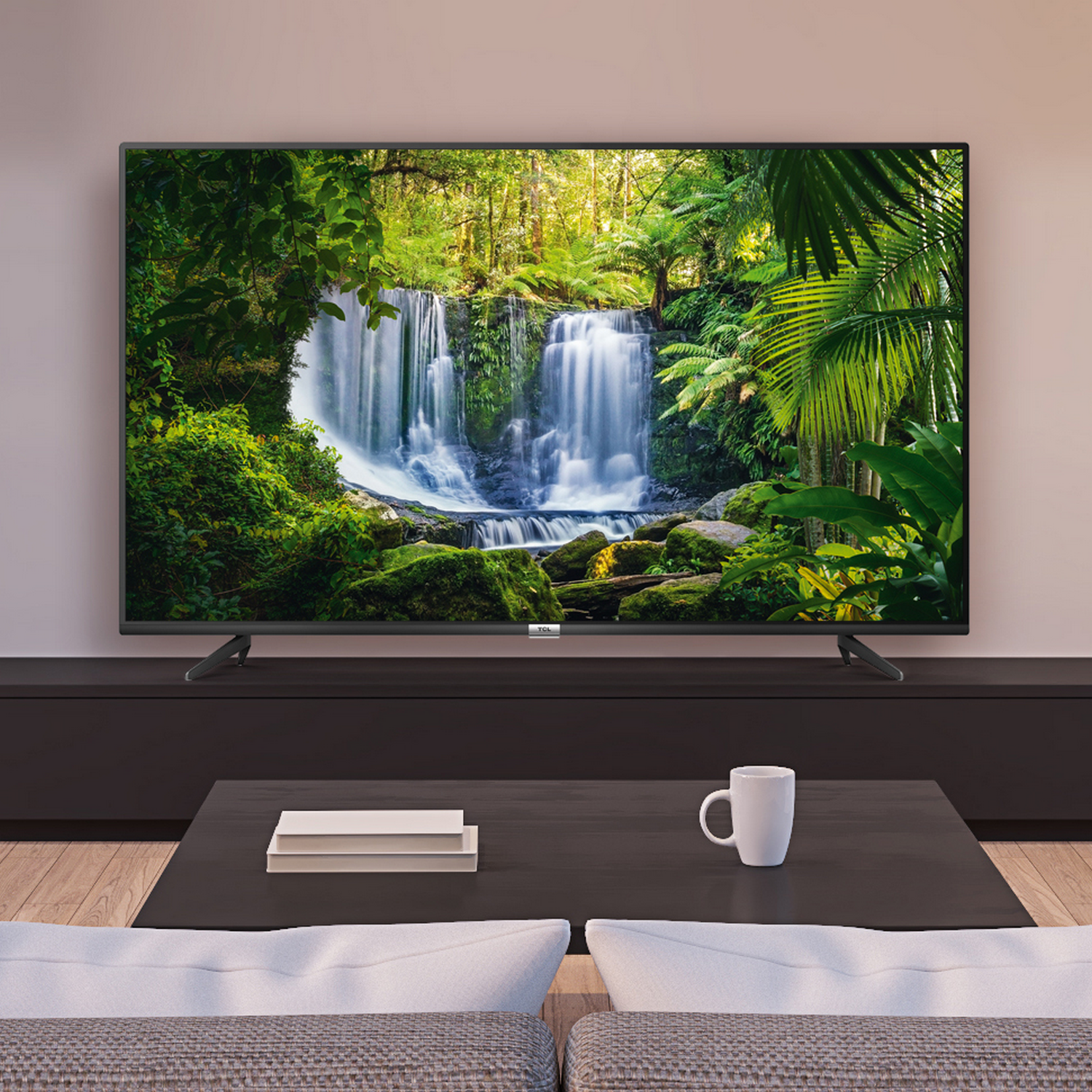Un televisor grande muestra una escena de cascada en un bosque. Una mesa de centro y un sofá están frente al televisor.