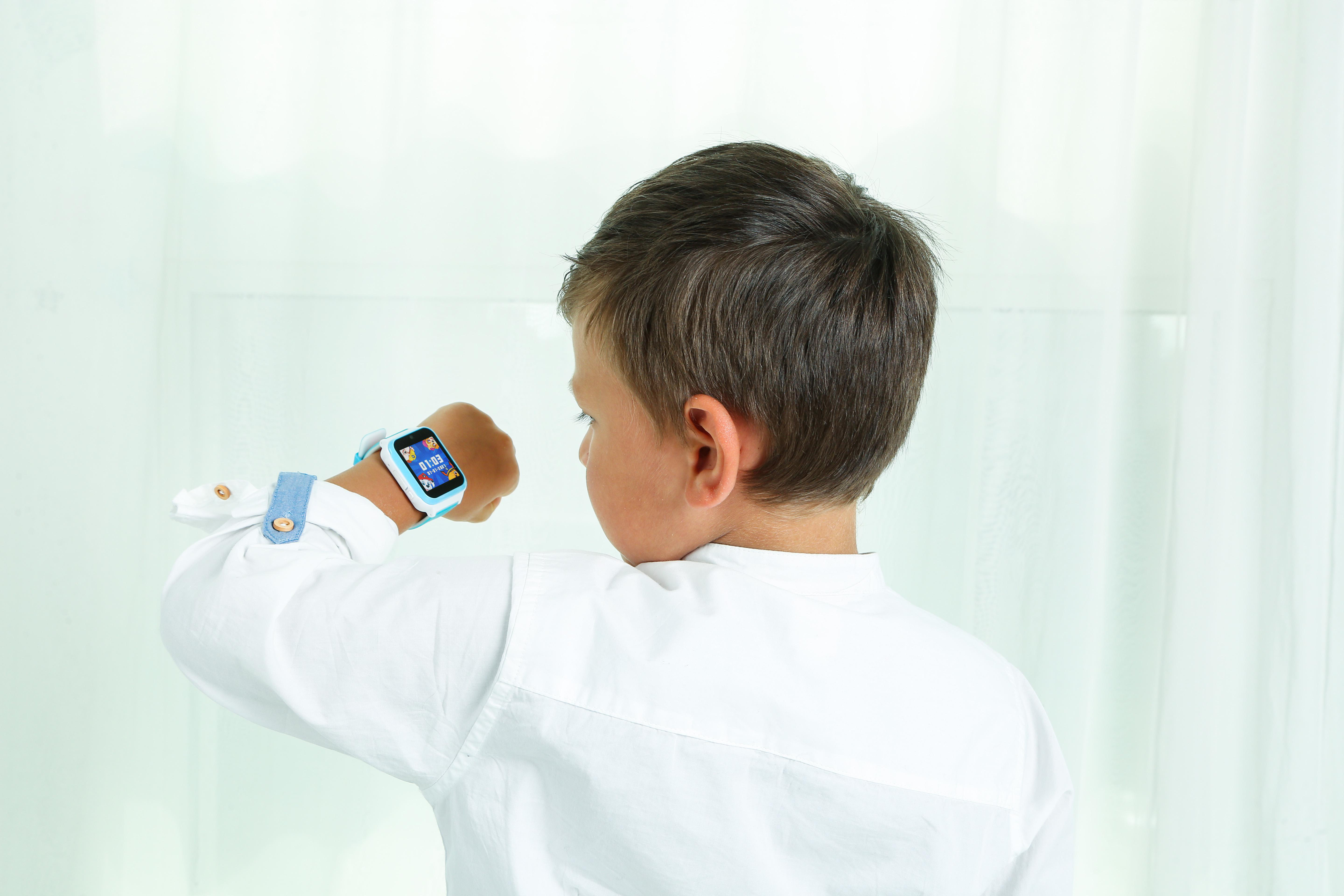 Junge mit Smartwatch am Handgelenk. Rückansicht, weißes Hemd.