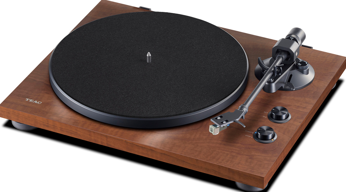 Une platine vinyle en bois avec un disque noir dessus. Le bras est en position de lecture.