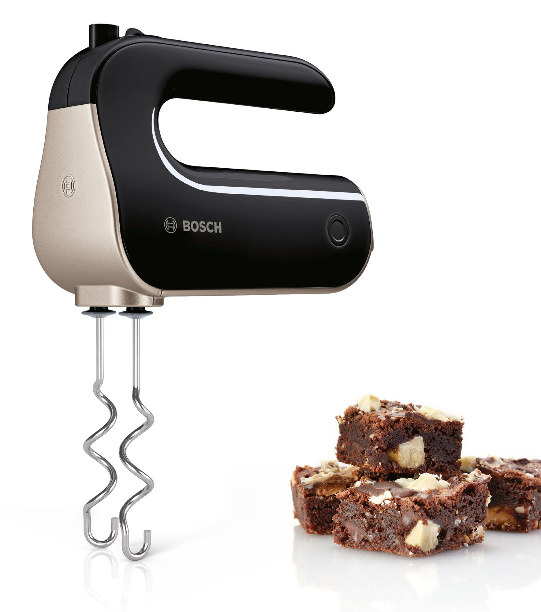 Egy fekete-arany kézi mixer, a háttérben brownie-kkal.