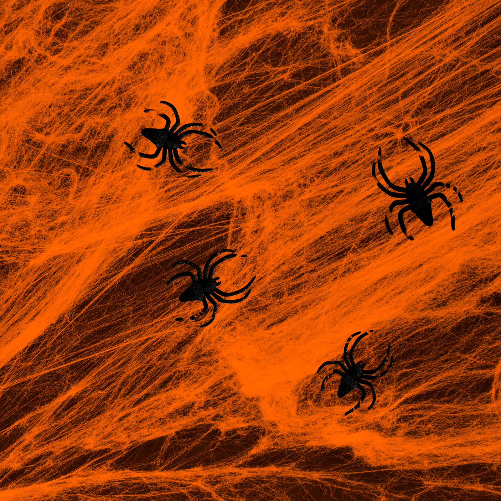 Halloween jelenet narancssárga pókhálóval és négy fekete pókkal sötétbarna háttér előtt.