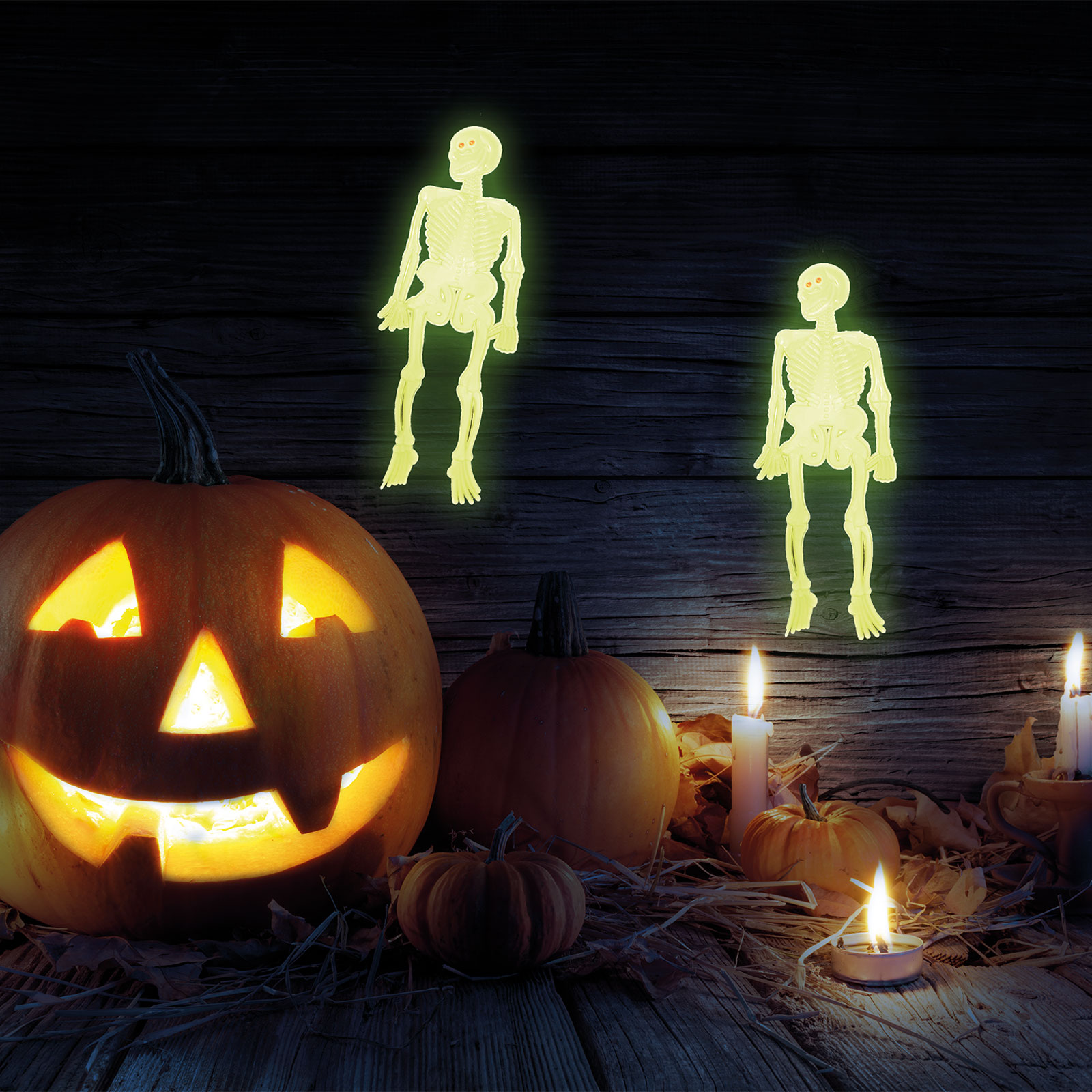 Halloween jelenet tökökkel, csontvázakkal és gyertyákkal egy fa felületen.