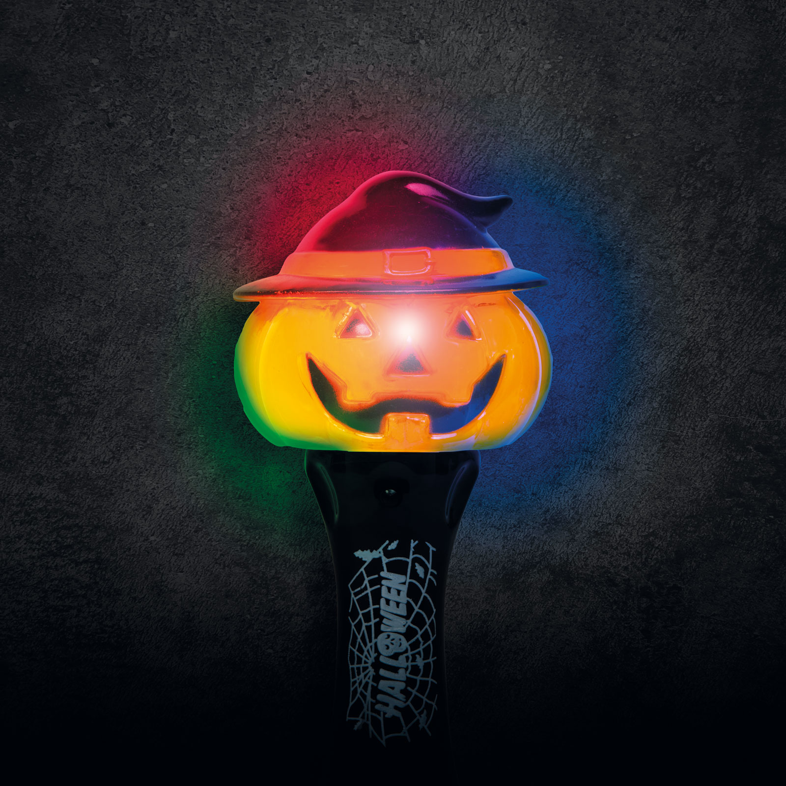 Egy Halloween tök alakú lámpa boszorkány kalappal, piros, zöld és kék fénnyel világít sötétszürke háttér előtt.