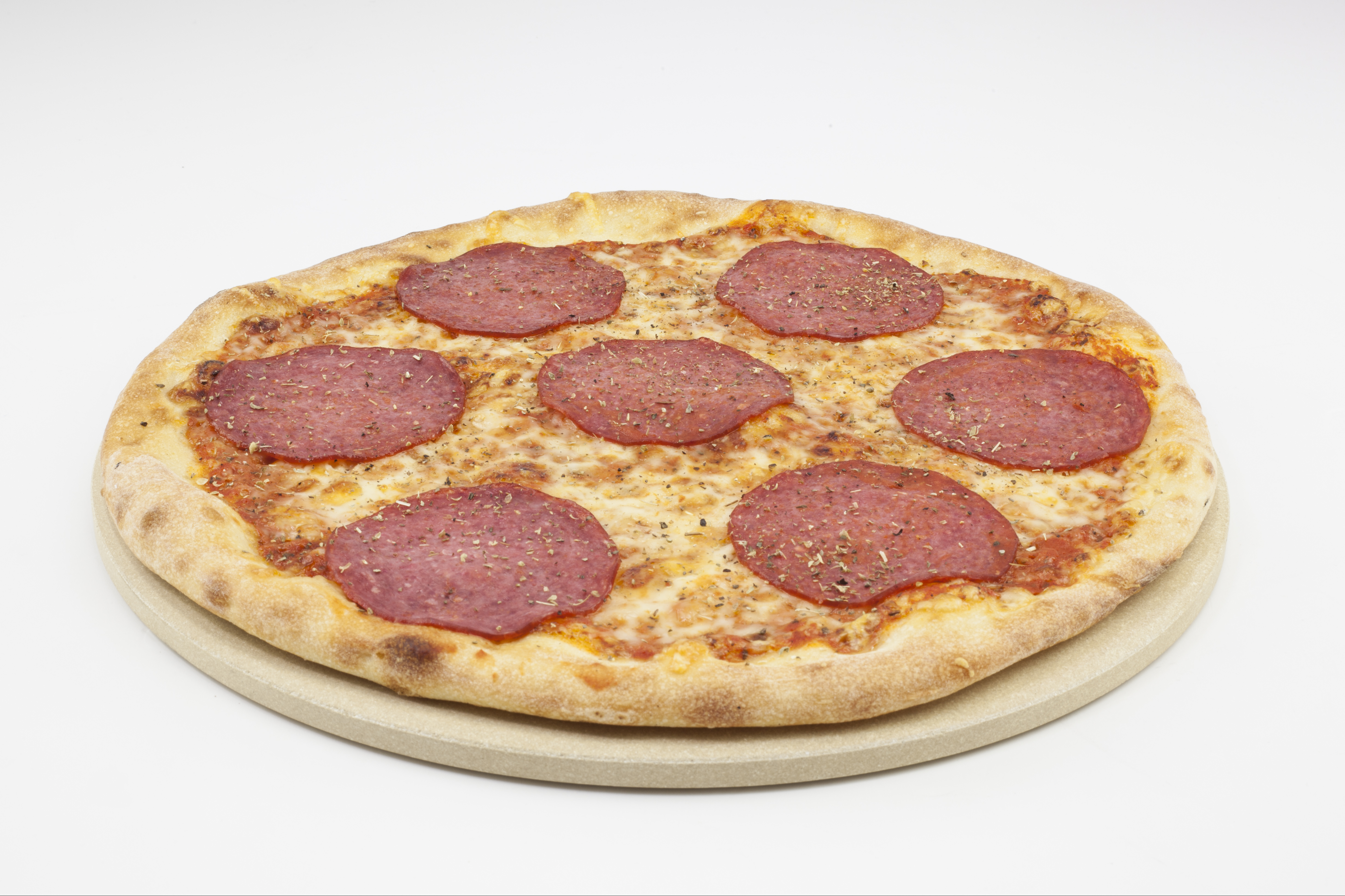 Eine Pizza mit Salami auf einem Steinplatten, vor weißem Hintergrund.