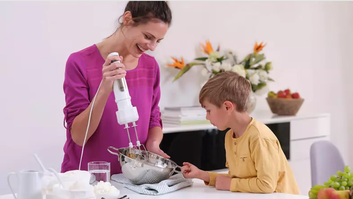 Femme et enfant utilisant un batteur à main dans une cuisine.