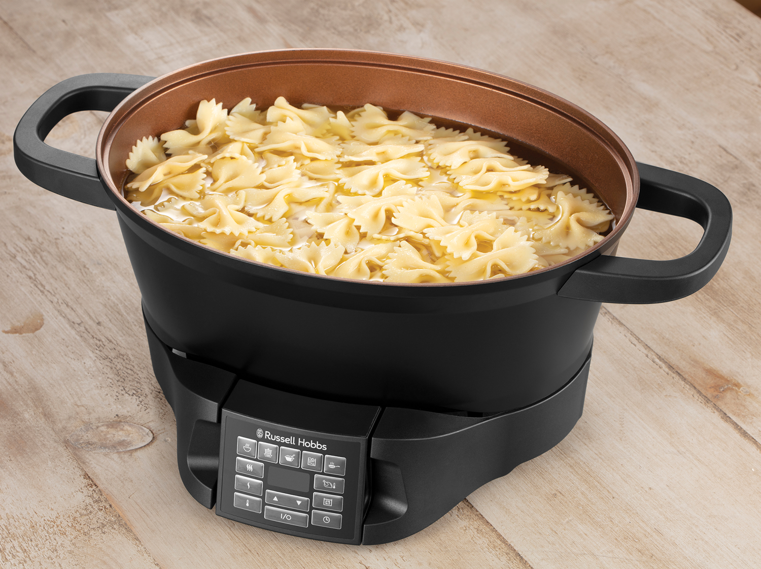 Farfalle pasta cooking in a black pot on a black base with control panel.