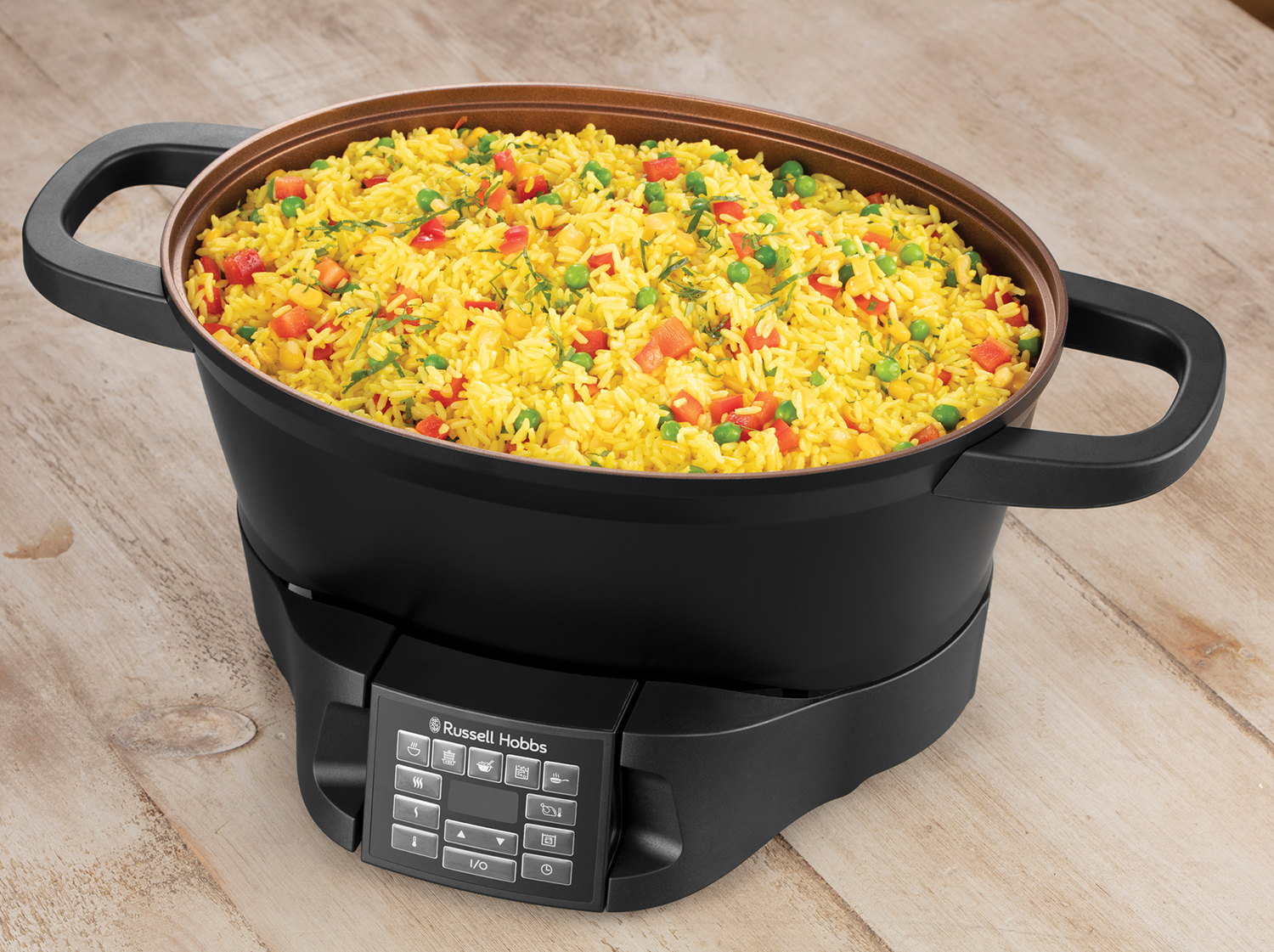 A black Russell Hobbs multi-cooker with yellow rice and vegetables inside, on a wooden surface.