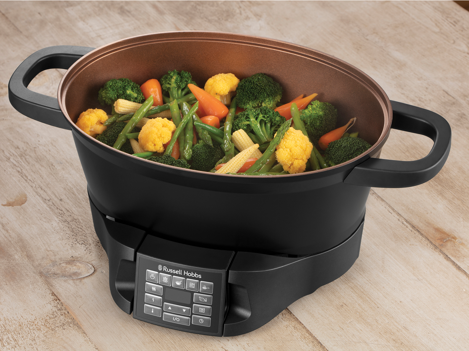 A black electric steamer filled with vegetables. It has a digital control panel on the front.
