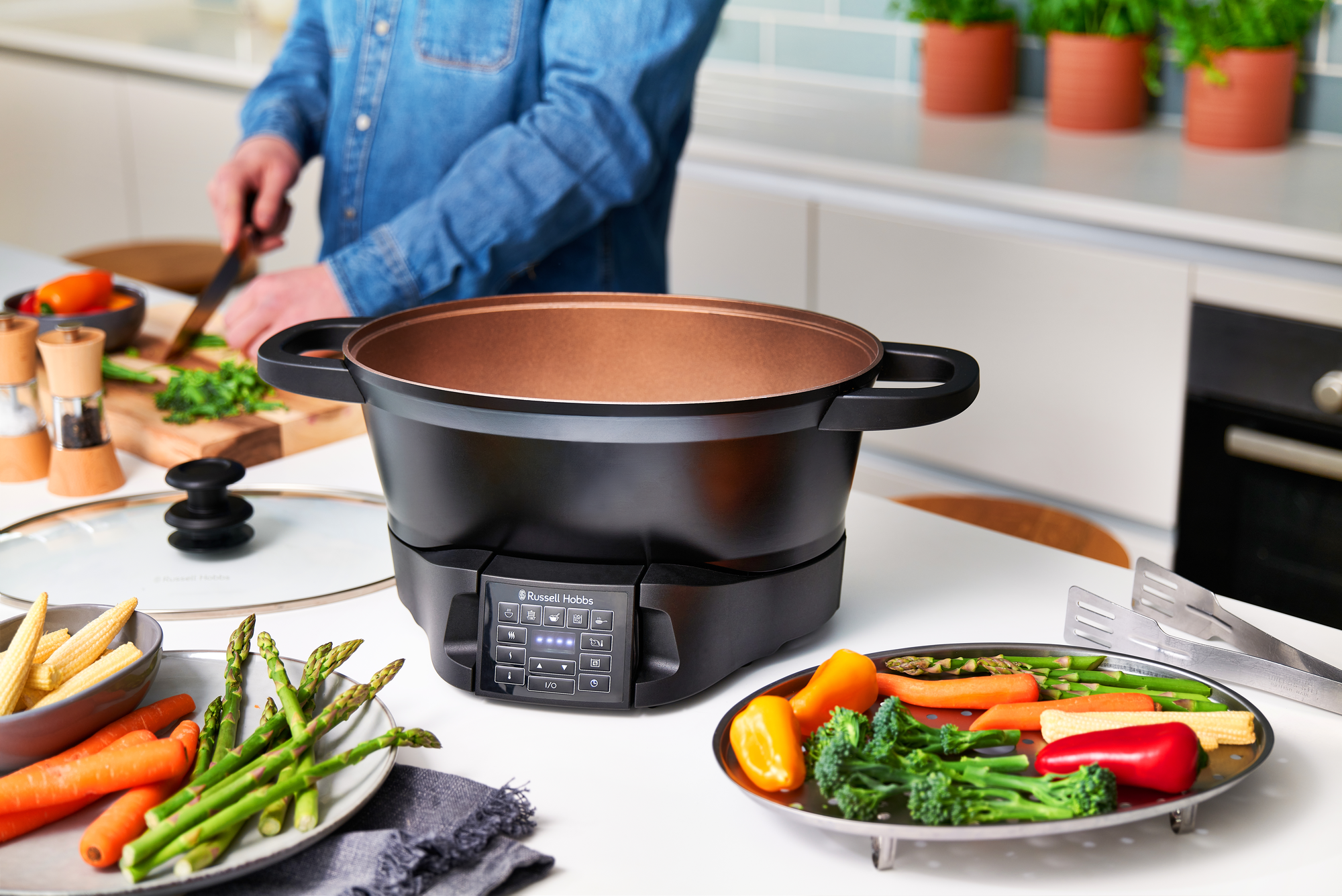 A black appliance with a copper interior, vegetables in front.