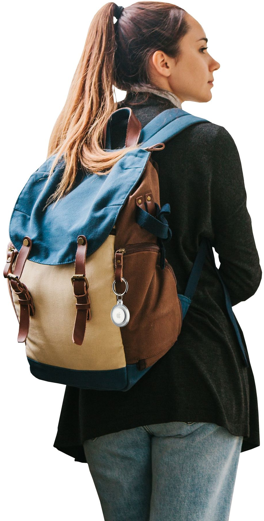 Eine Frau mit Rucksack steht mit einem Schlüsselanhänger, an dem ein silbernes AirTag befestigt ist.