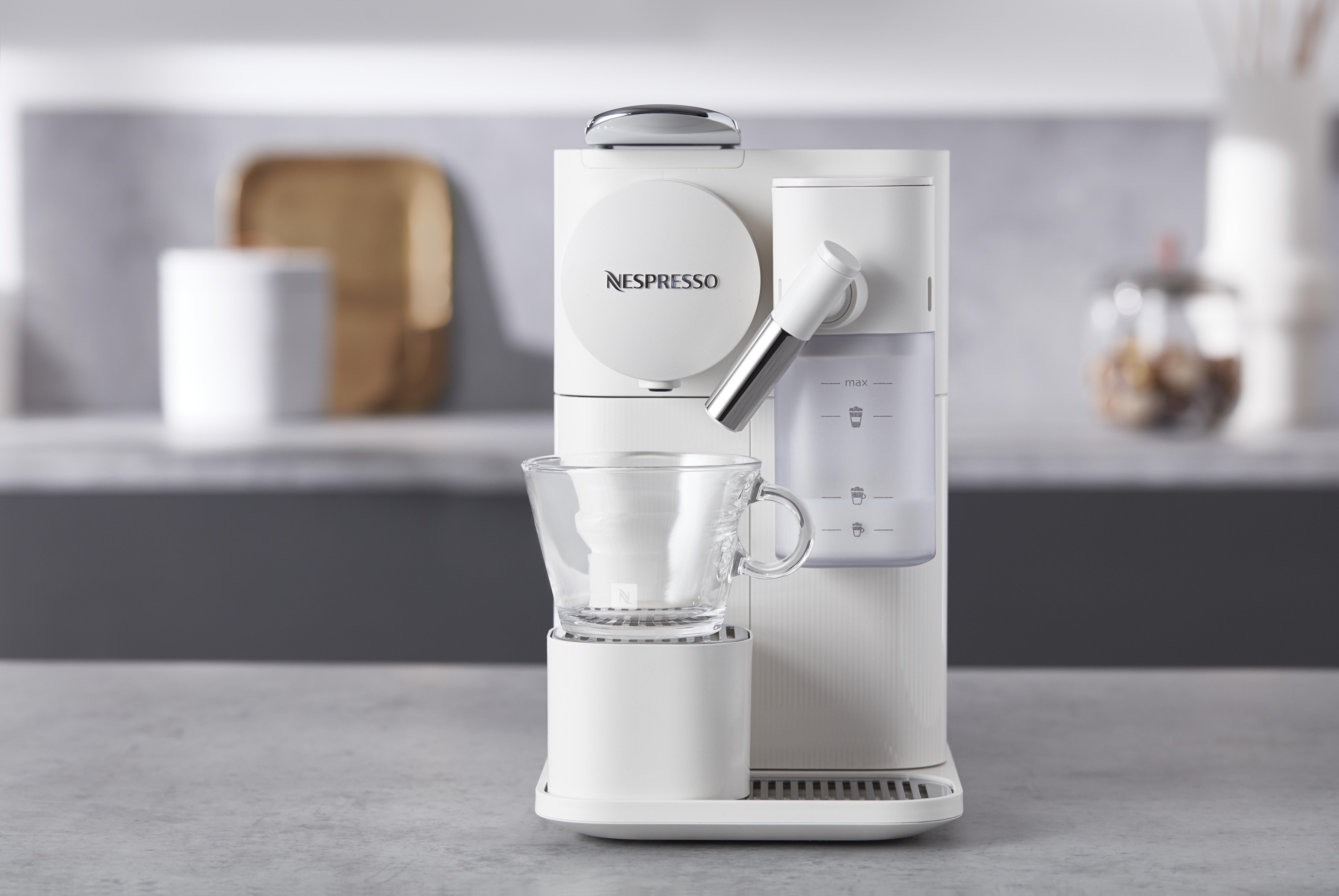 Eine weiße Nespresso Kaffeemaschine mit Tasse, Wassertank und silbernem Ausguss.