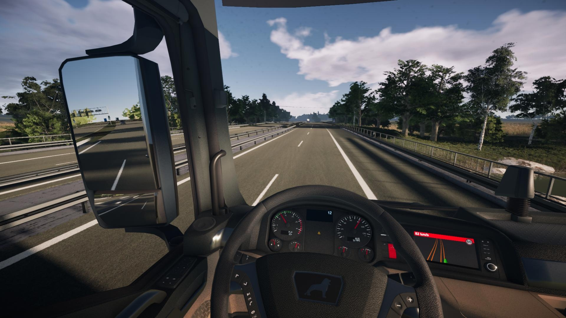 Vista dall'interno di una cabina di camion che guida in autostrada, con cielo blu e alberi visibili.