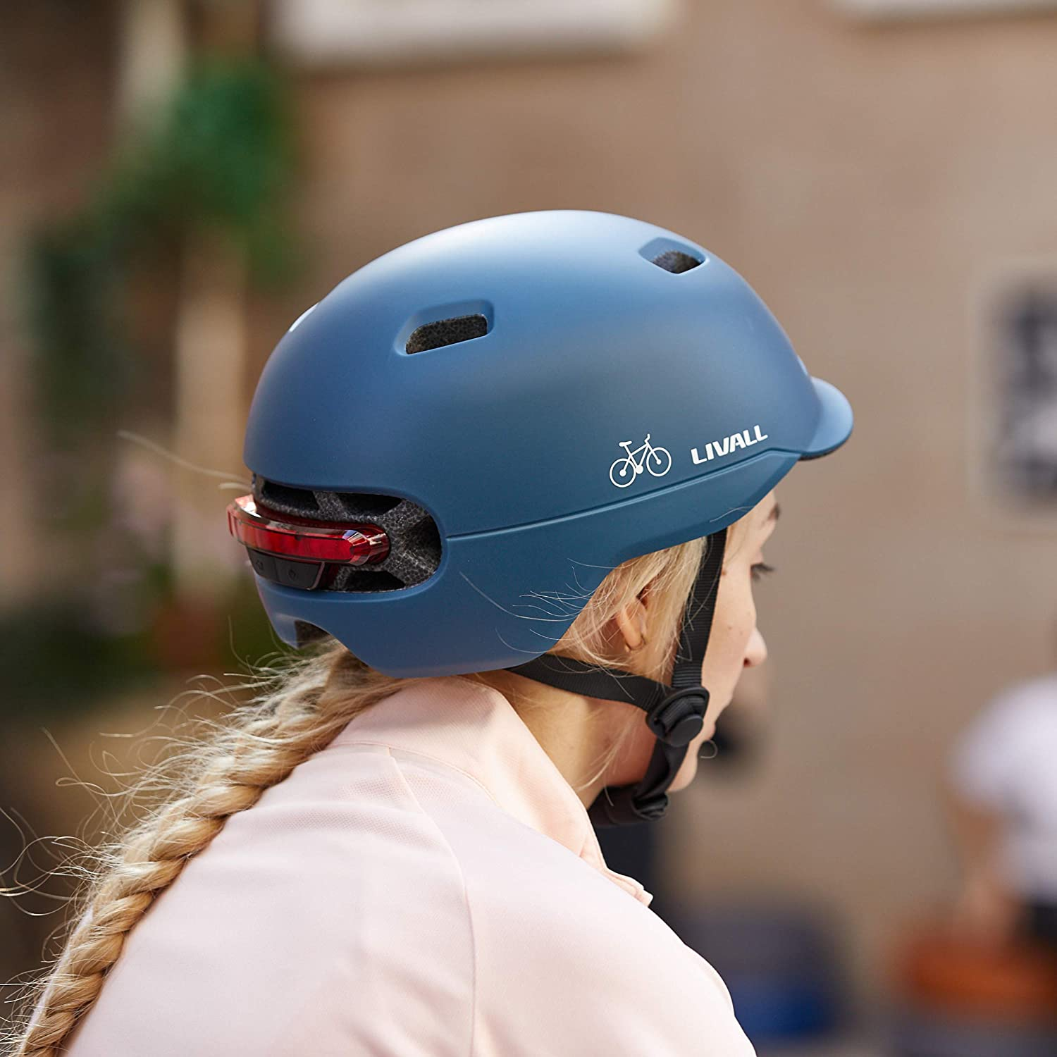 Un casco de bicicleta azul con una mujer. La mujer lleva el casco y tiene el pelo rubio.