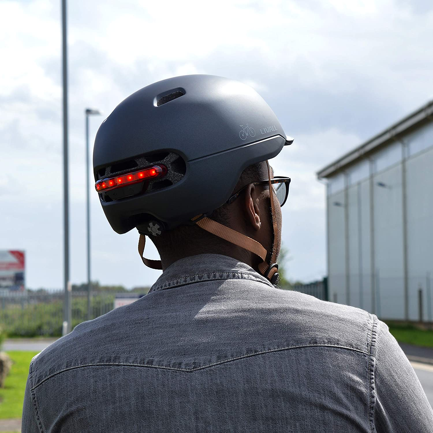 Una persona con un casco gris con una luz roja en la parte trasera.
