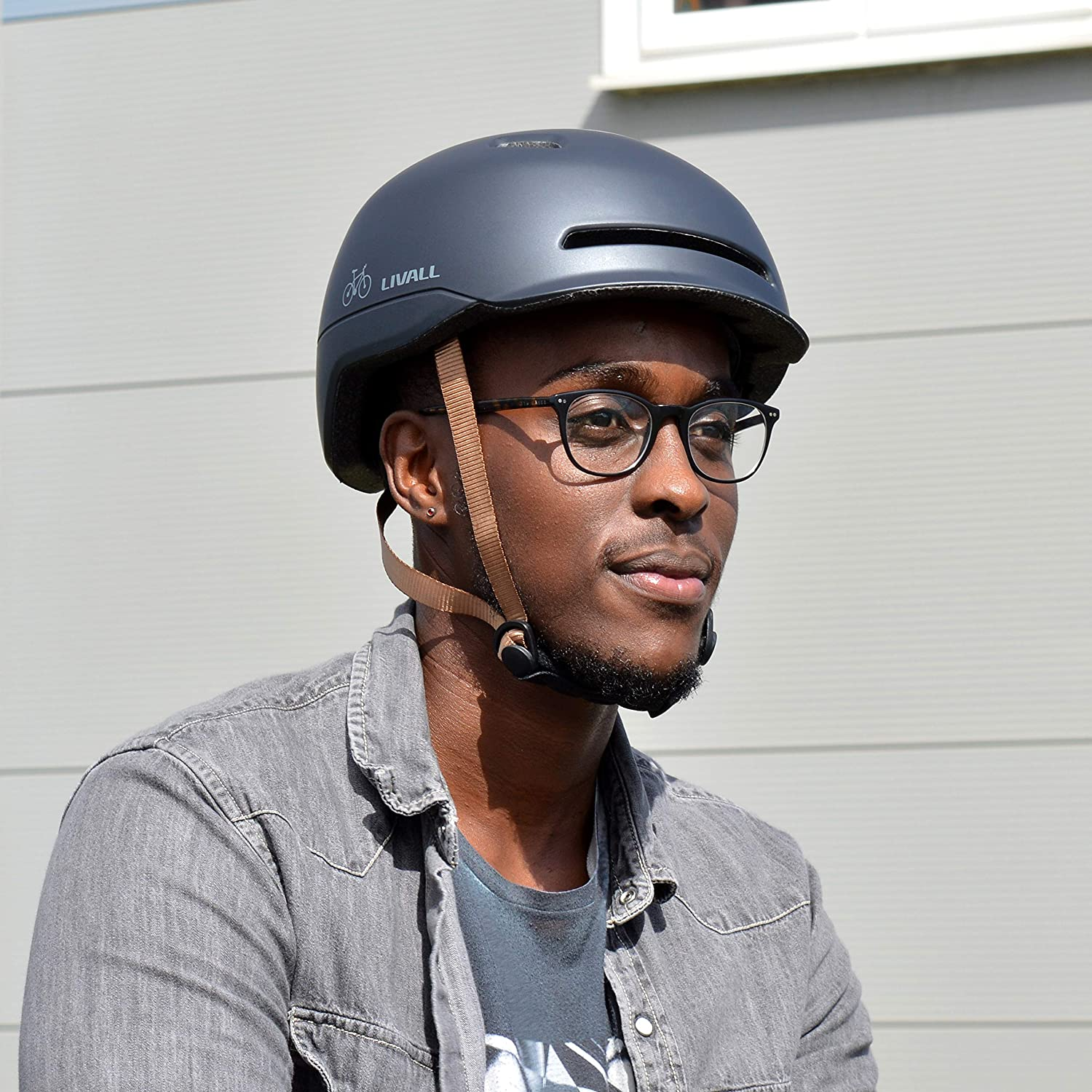 Hombre con casco gris oscuro y gafas, al aire libre, de día.