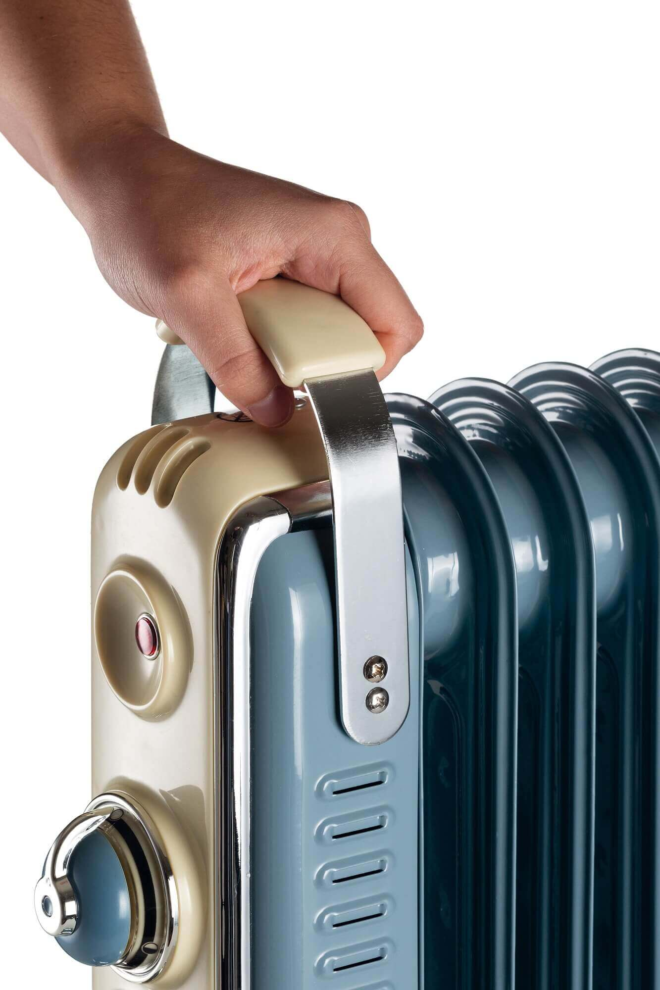 Mano che tiene un radiatore ad olio retrò beige e blu. Accenti cromati e quadrante di controllo visibili.