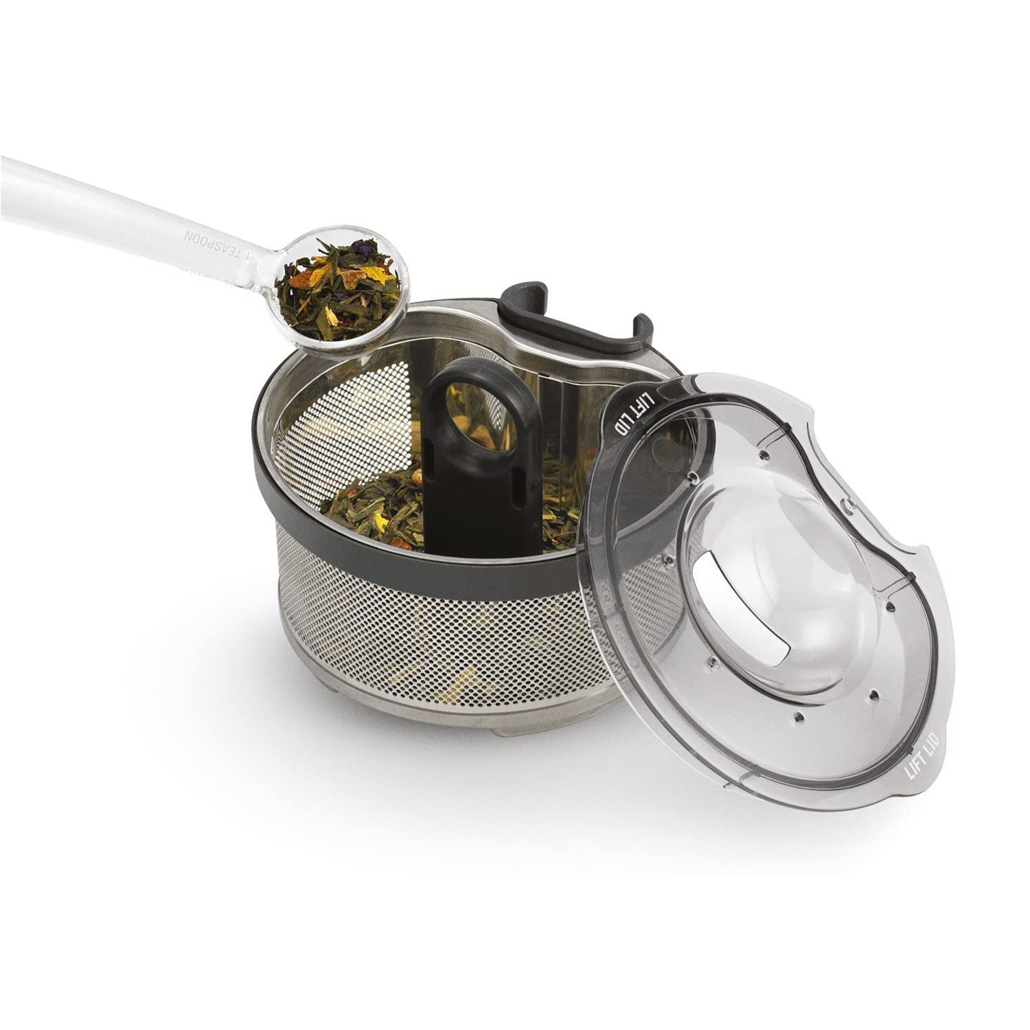 Infusore per tè con foglie di tè, cucchiaio e coperchio trasparente, su sfondo bianco.