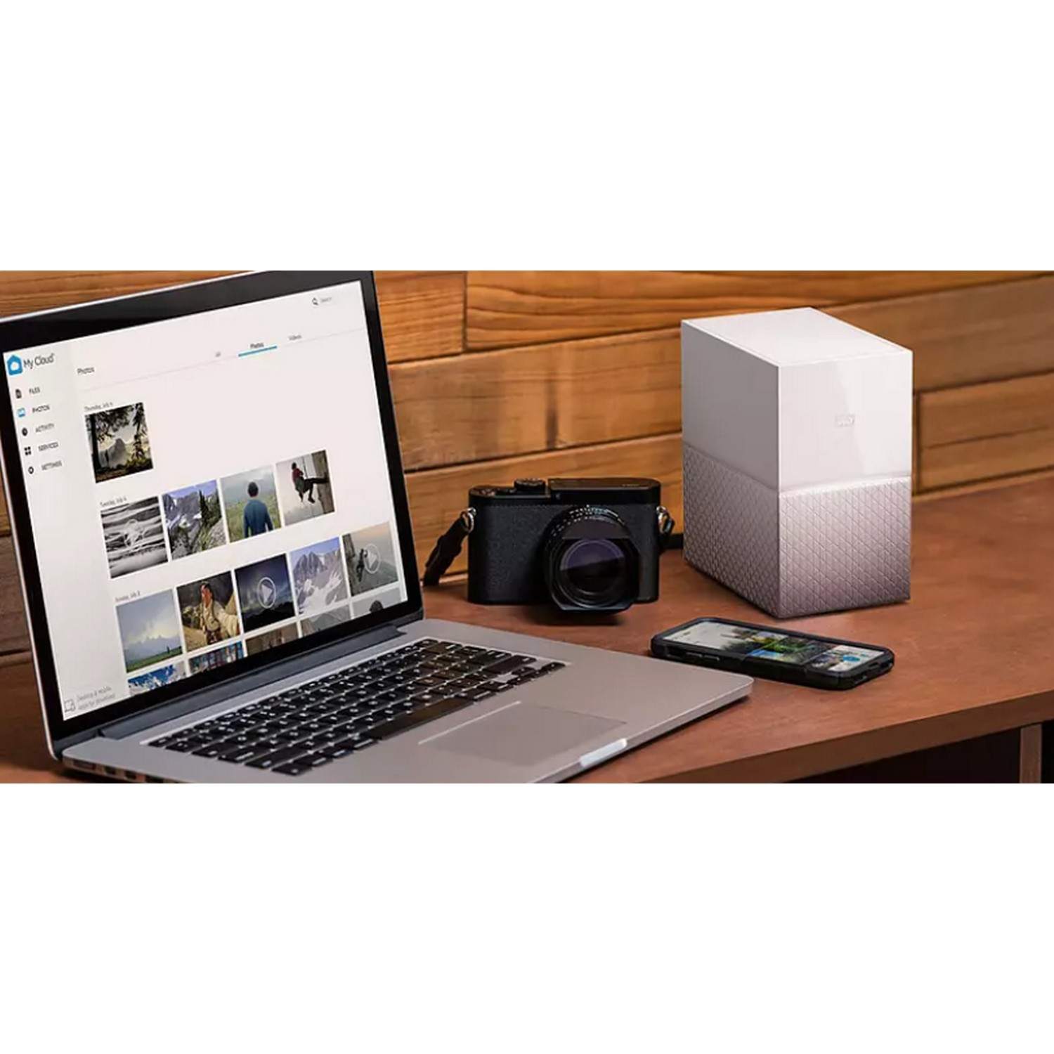 Ordenador portátil, cámara, teléfono y disco duro externo en una mesa de madera.