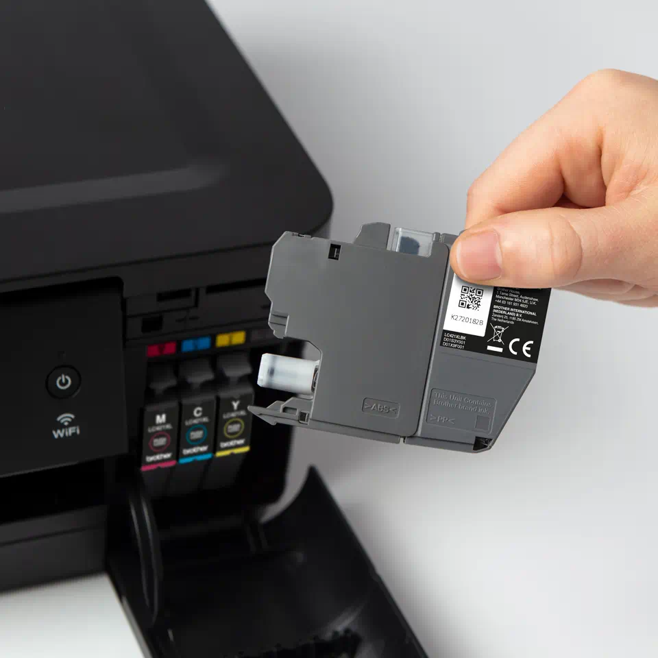 Hand, die eine Druckerpatrone neben einem Drucker hält. Weißer Hintergrund.