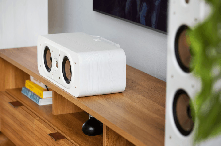 Witte luidspreker op een houten kast met een tv.
