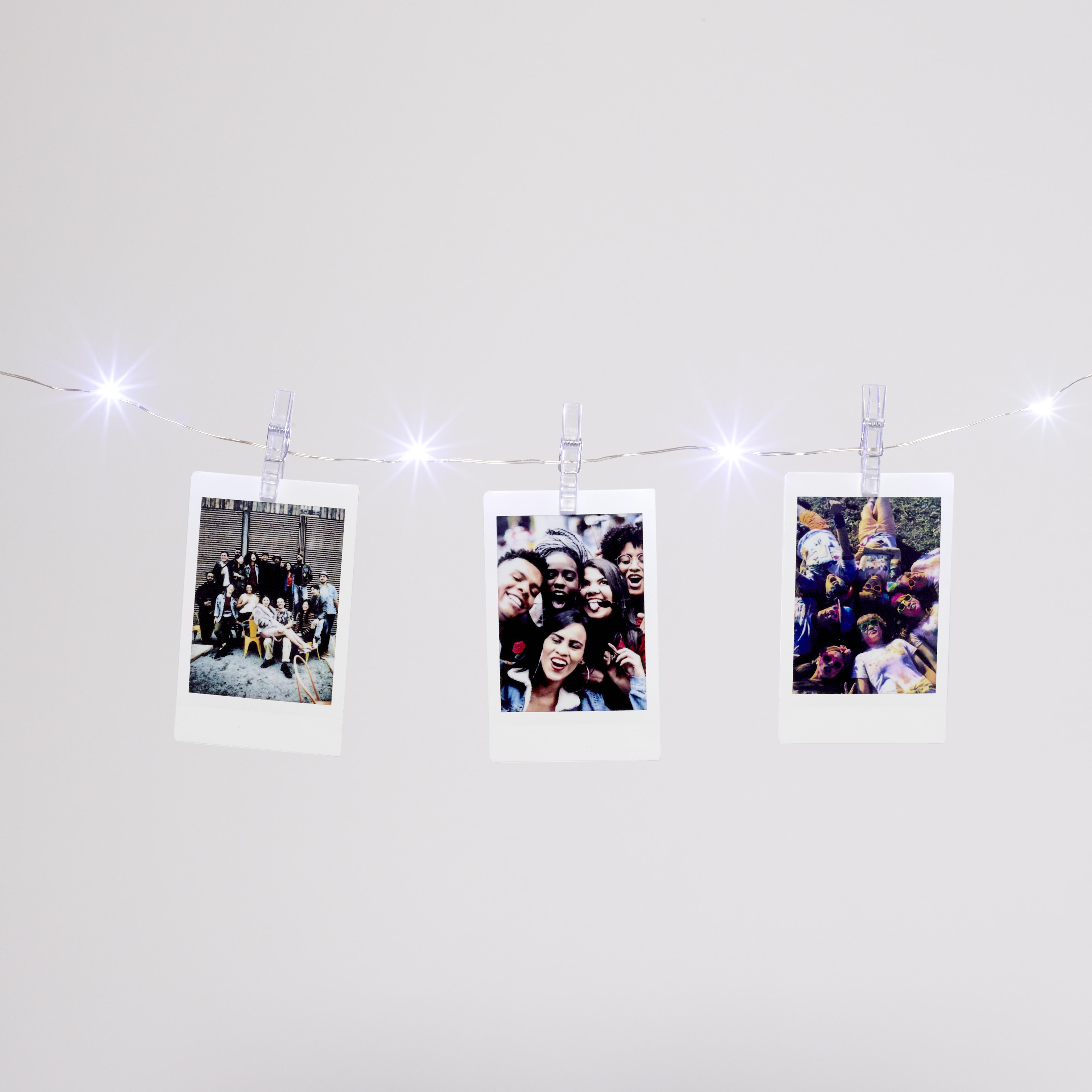 Drei Fotos, die an einer Schnur hängen. Die Fotos zeigen verschiedene Gruppen lächelnder Menschen.