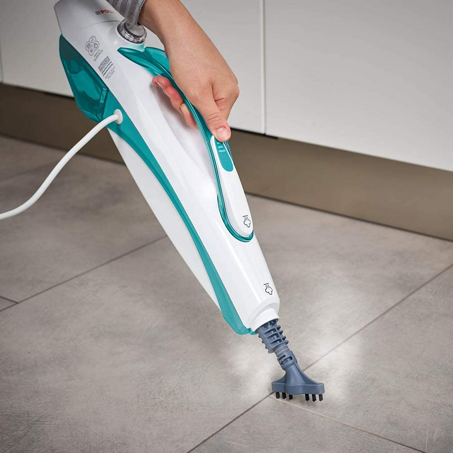 Una persona usando una limpiadora de vapor portátil en un suelo embaldosado.