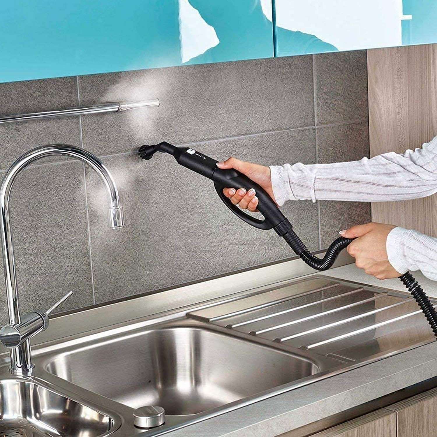 Mano limpiando superficie con limpiador a vapor en cocina.