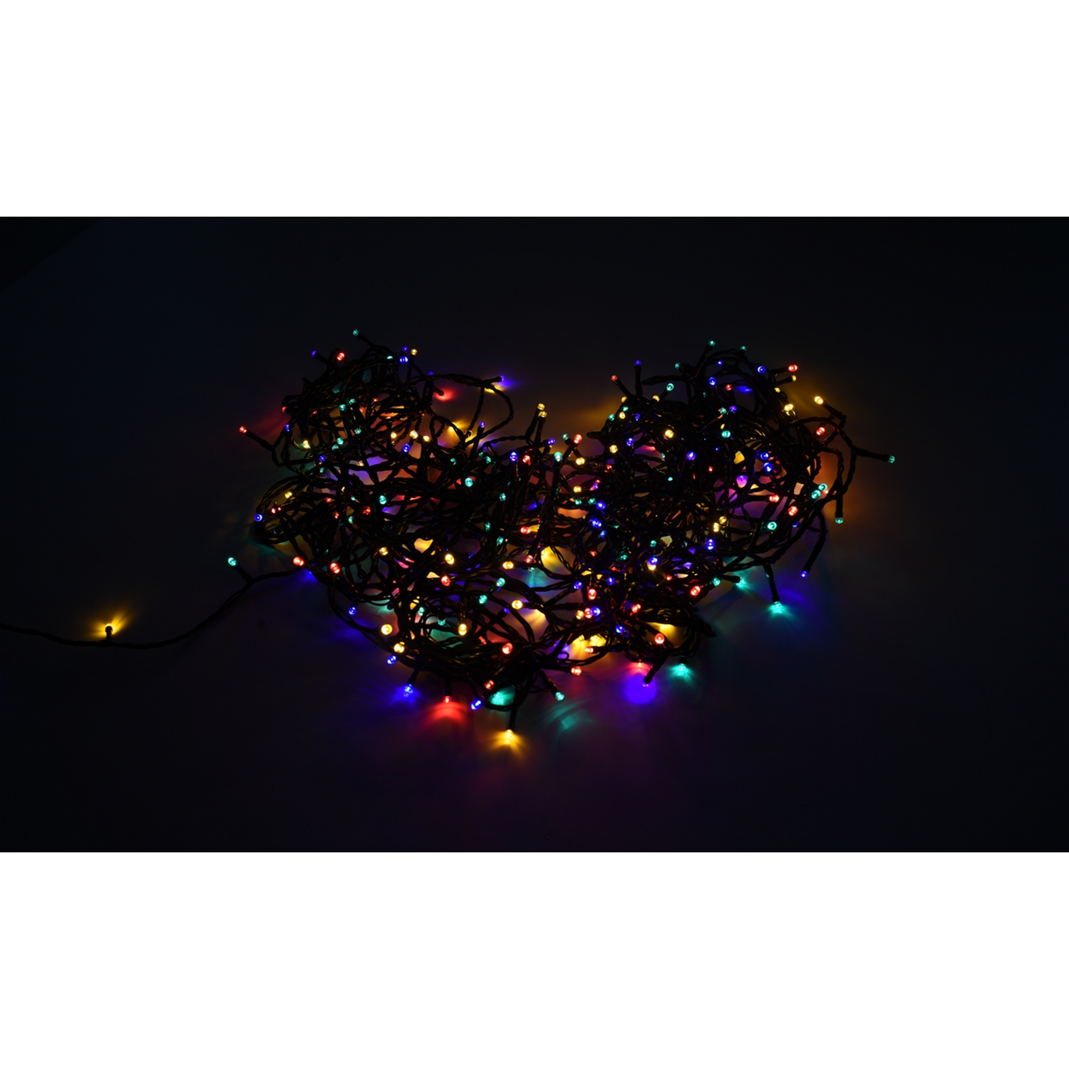 Un montón enredado de luces navideñas multicolores sobre una superficie negra, con un fondo oscuro.