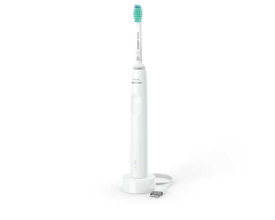 Fehér Philips Sonicare fogkefe töltőállomáson. Zöld és kék sörték.