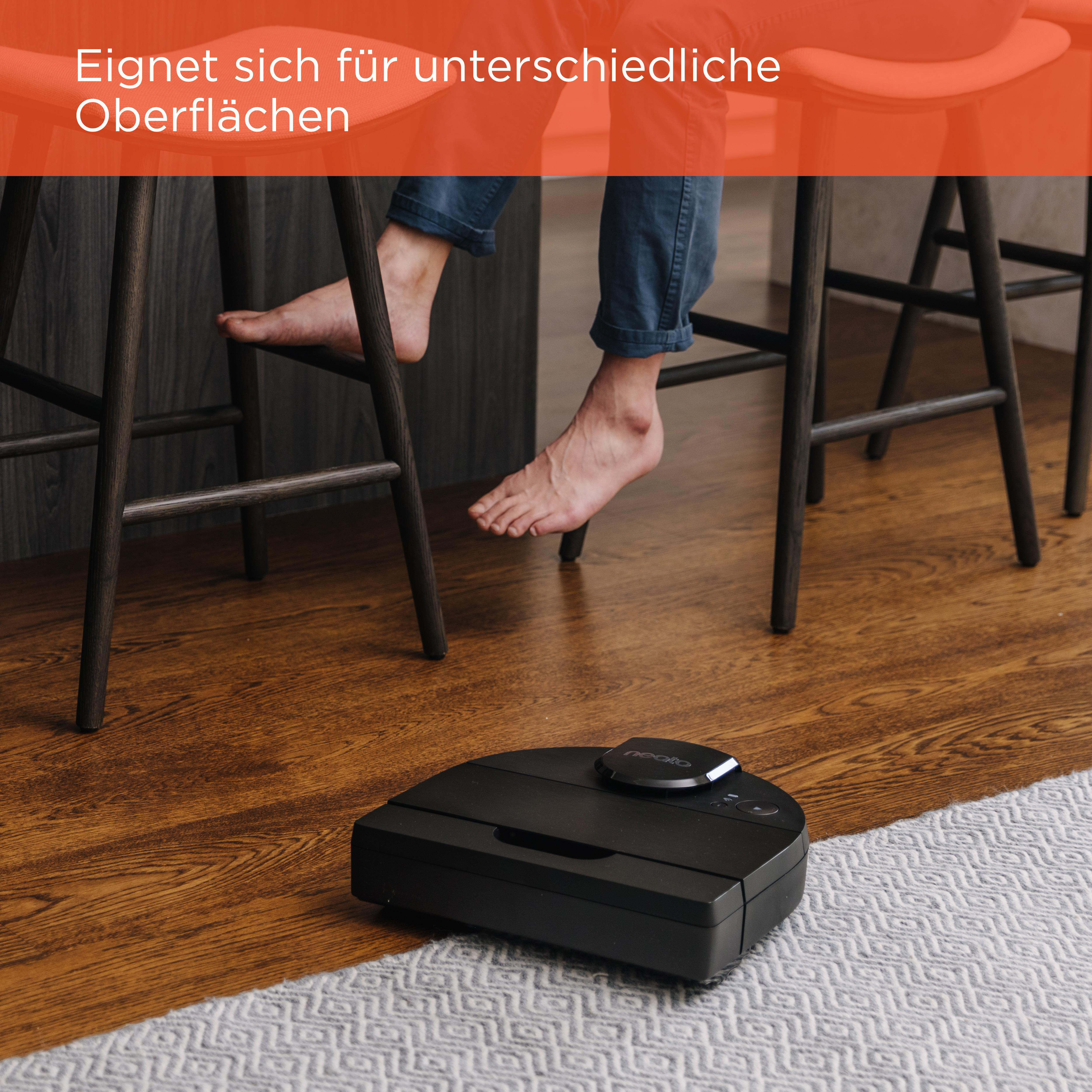 Barfuß nahe schwarzem Staubsauger auf Holzboden.
