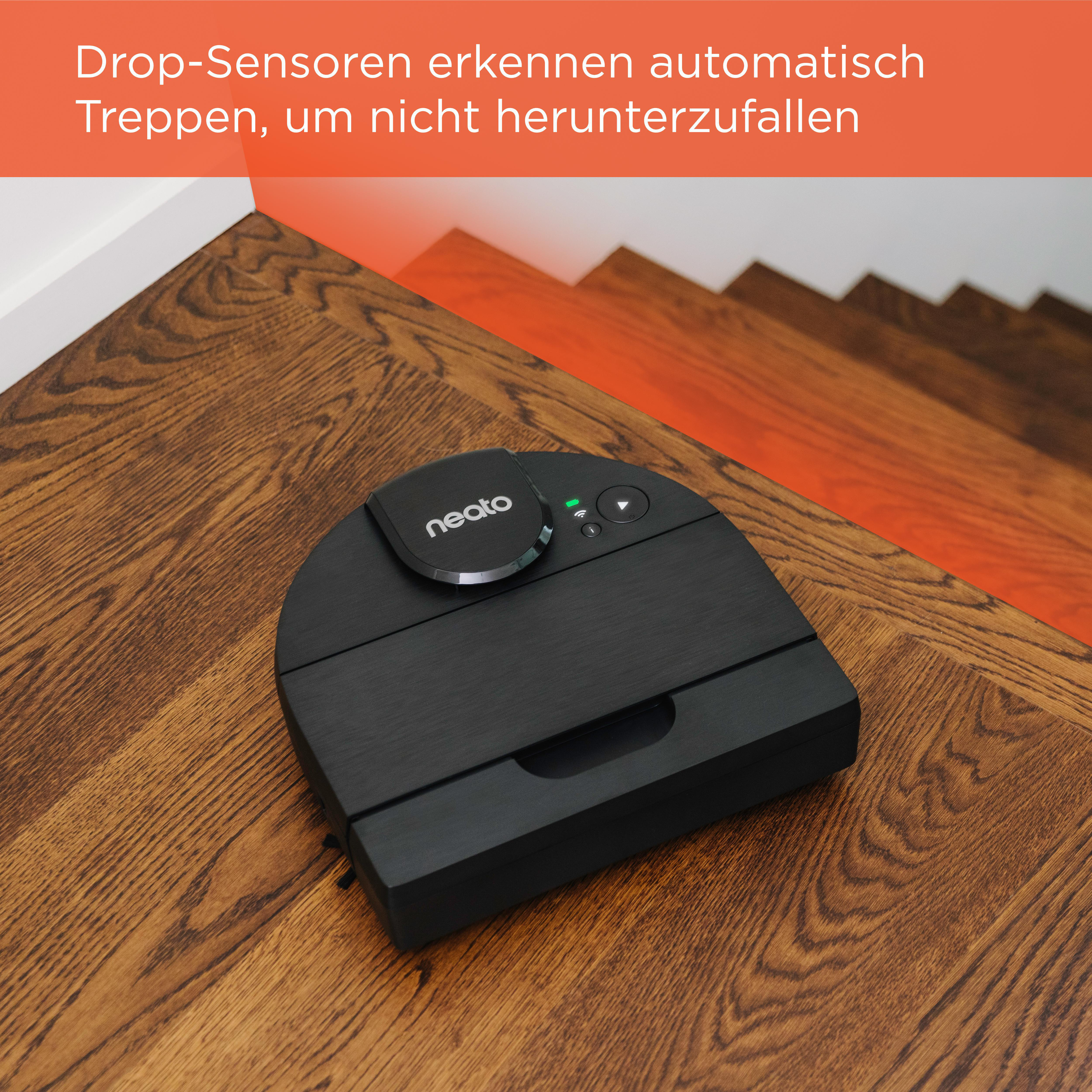 Roboter-Staubsauger in der Nähe einer Treppe. Er ist schwarz, die Treppe aus Holz.